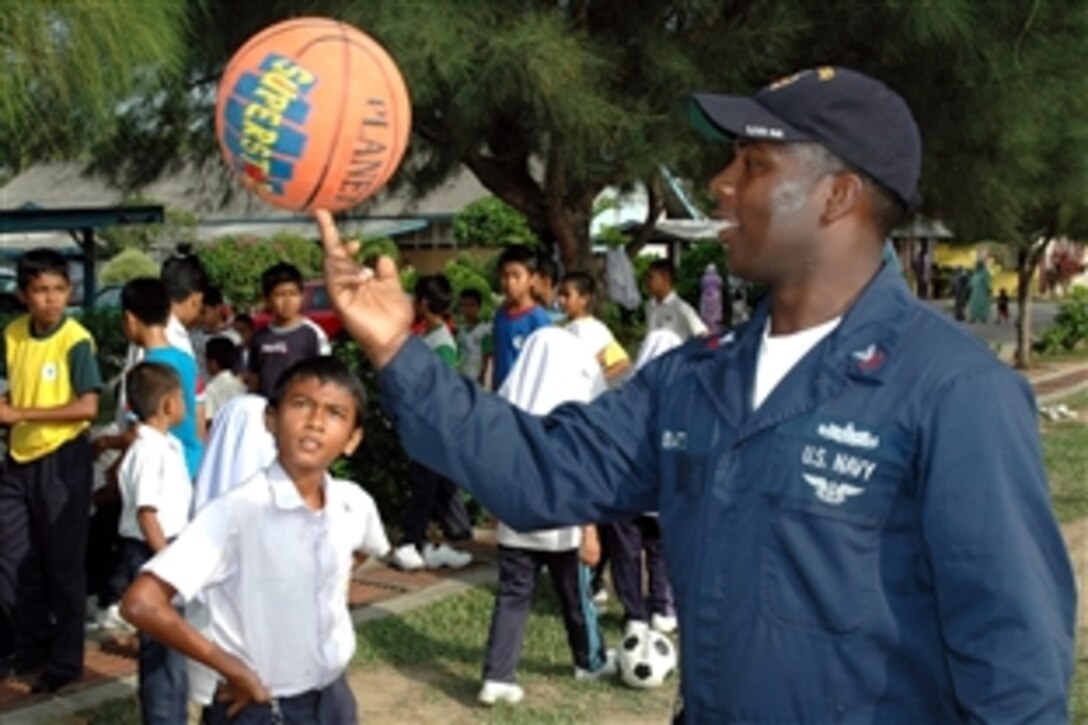 U.S. Navy Petty Officer 1st Class Andre Batts demonstrates to children the proper way to spin a basketball on a fingertip during a community relations project at Sekolah Kebangsaan Kijal elementary school in Chukau, Malaysia, July 7, 2008. The visit is part of Cooperation Afloat Readiness And Training 2008, an annual series of bilateral maritime training exercises among the United States and six Southeast Asia nations designed to build relationships and enhance the operational readiness of parti