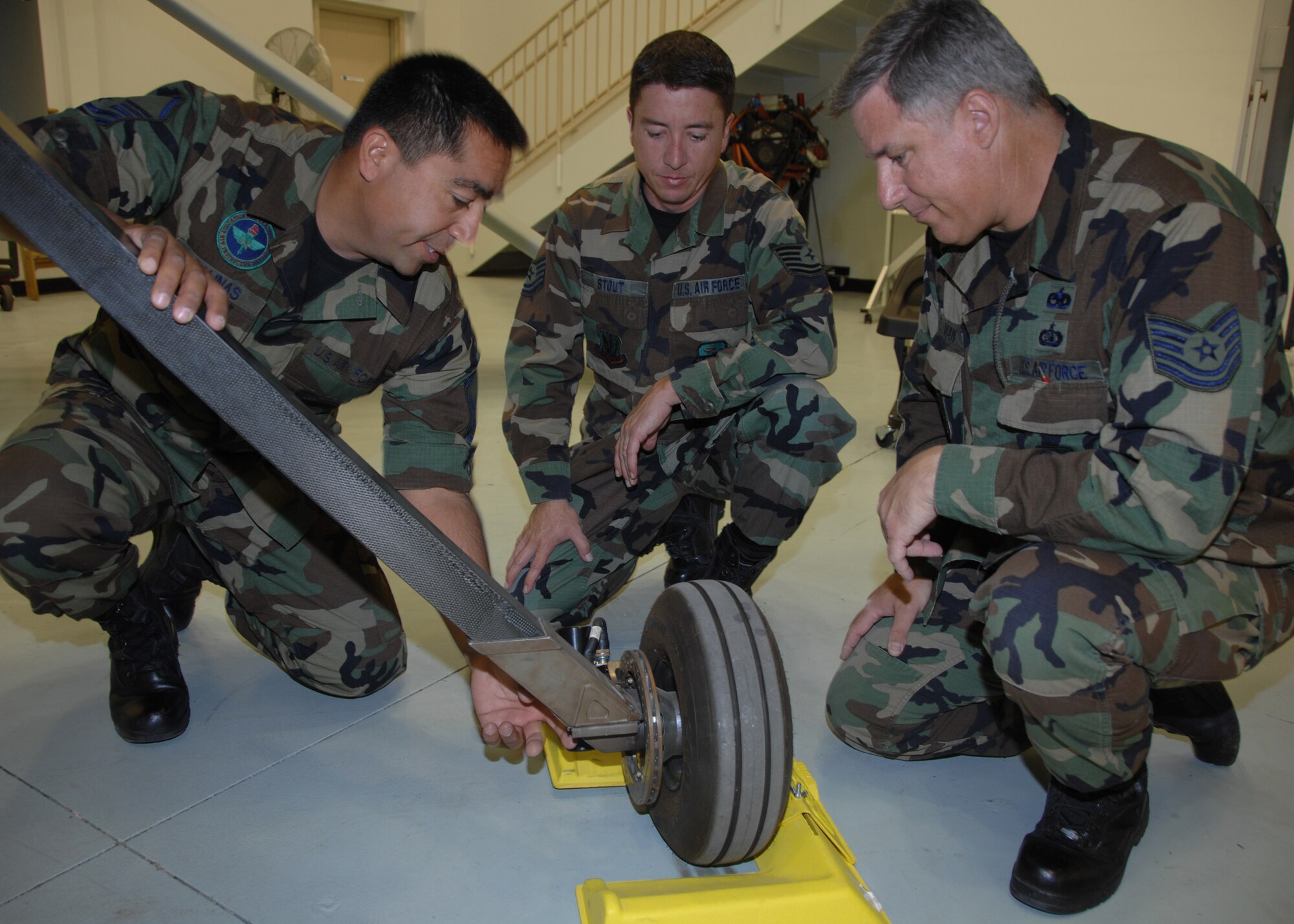 Field Training Detachment superintendent and instructor Master Sgt. Bill Salinas
(left) explains the main landing gear tow-in rigging procedure for the MQ-1A Predator to Technical Sgts. Chris Stout (center) and Kevin Shellman, 163d Aircraft Maintenance Squadron crew chiefs. This procedure is required when removing and replacing the Predator’s main landing gear. Sergeants Stout and Shellman were in the last class taught before the FTD moved to a new, larger facility. (U.S. Air Force photo by Tech. Sgt. Julie Avey)