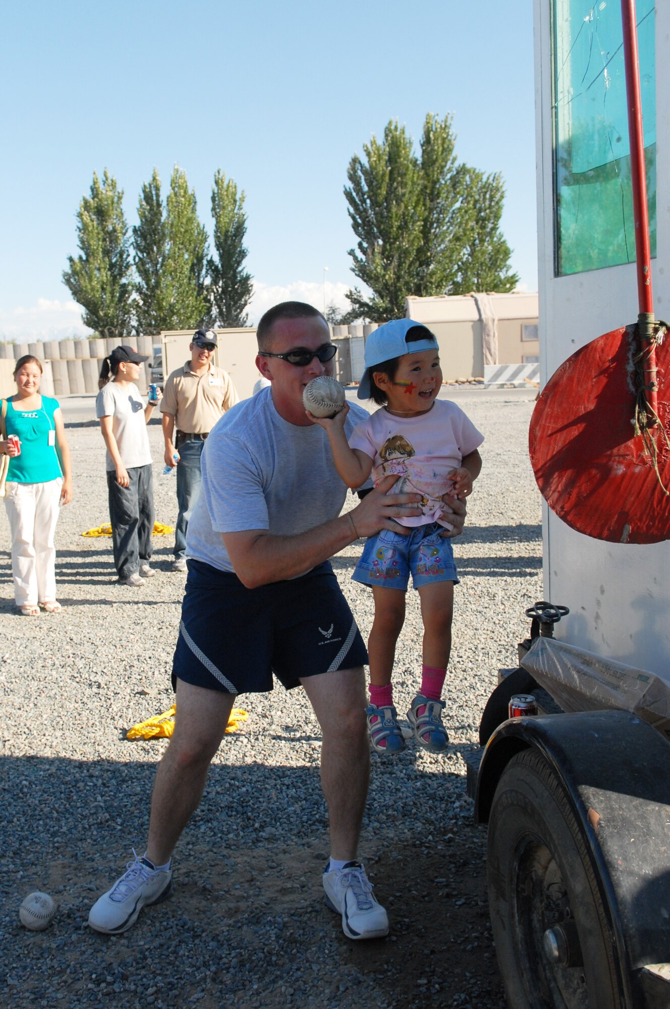 MANAS AIR BASE, Kyrgyz Republic --Staff Sgt. Ronald Reyome, from the 376th Expeditionary Theater Distribution Center, helps the local children throw balls at the dunk tank during the Manas Air Base contractor and family appreciation day, July 11, at Manas AB, Kyrgyz Republic. Roughly 600 guests attended the activities ranging from face painting, barbeque, and a Tops in Blue concert. (U.S. Air Force photo / Airman 1st Class Ruth Holcomb)