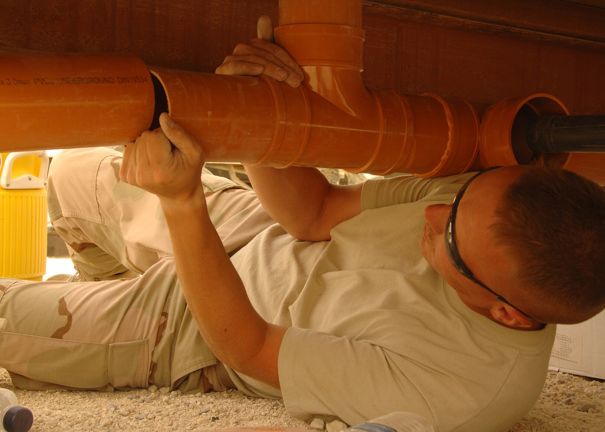 SOUTHWEST ASIA -- Tech. Sgt. Michael Biggs, a member of the 386th Expeditionary Civil Engineer Squadron, installs a PVC pipe under a new K-9 kennel on July 11 at a base in Southwest Asia. The 386th Expeditionary Civil Engineer Squadron is completing a project to increase the square footage of the K-9 kennels for the 386th Expeditionary Security Forces Squadron. Sergeant Biggs is deployed from the 108th Air Refueling Wing, McGuire Air Force Base, N.J. (U.S. Air Force photo/Tech. Sgt. Raheem Moore)