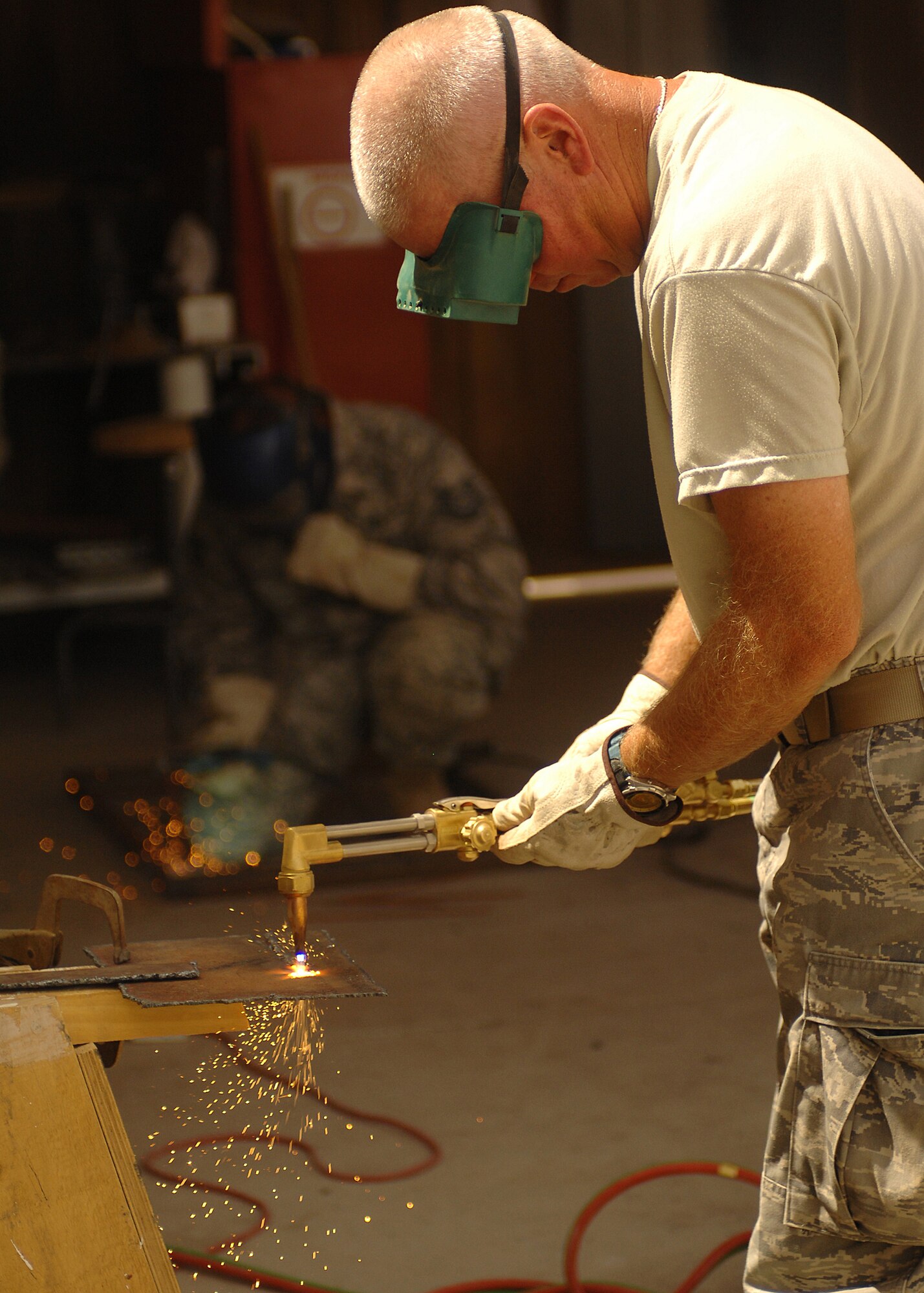 SOUTHWEST ASIA -- Staff Sgt. Mark Gorton, foreground, uses a blow torch to cut metal, while Tech. Sgt. Anthony Roman welds a frame together on July 11 at a base in Southwest Asia. The 386th Expeditionary Civil Engineer Squadron is completing a project to increase the square footage of the K-9 kennels for the 386th Expeditionary Security Forces Squadron. The metal frames will be used to build new ramps for the dogs. Sergeant Roman is deployed from the 156th Airlift Wing, Muniz Air National Guard Base, Puerto Rico. Sergeant Gorton is deployed from the 136th Airlift Wing, Fort Worth, Texas. (U.S. Air Force photo/Tech. Sgt. Raheem Moore)