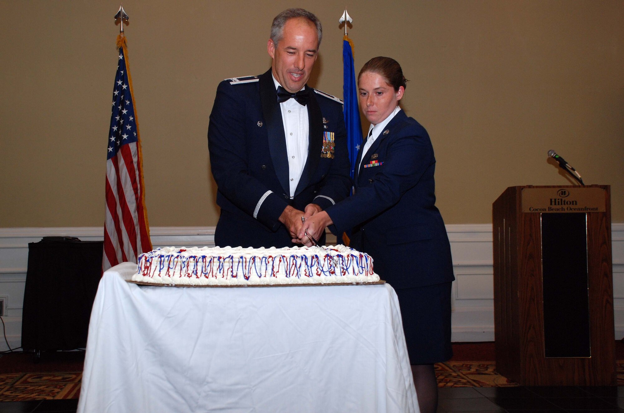 PATRICK AIR FORCE BASE, Fla. - Col. Steven W. Kirkpatrick, commander of the 920th Rescue Wing, get the first bite of the cake at the Wing's third annual military ball during the July Unit Training assembly. Colonel Kirkpatrick is assisted in cutting the cake by Airman Basic Alisha Dixon from the 920th Security Forces Squadron following the Air Force tradtition of having the highest and lowest ranking individuals in the room cut the cake with the ceremonial sword.  (U.S. Air Force photo / Master Sgt. Raymond F. Padgett) 