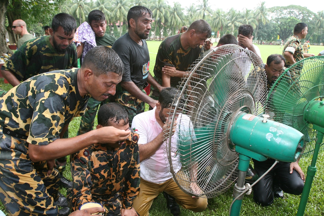 Bangladesh service members and local law-enforcement personel huddle around a fan for relief after a familarization exercise with oleoresin capsicum (pepper) spray July 14 during Non-Lethal Weapons Executive Seminar 2008 here. The training provides a better understanding of the effects of pepper spray before it is employed.