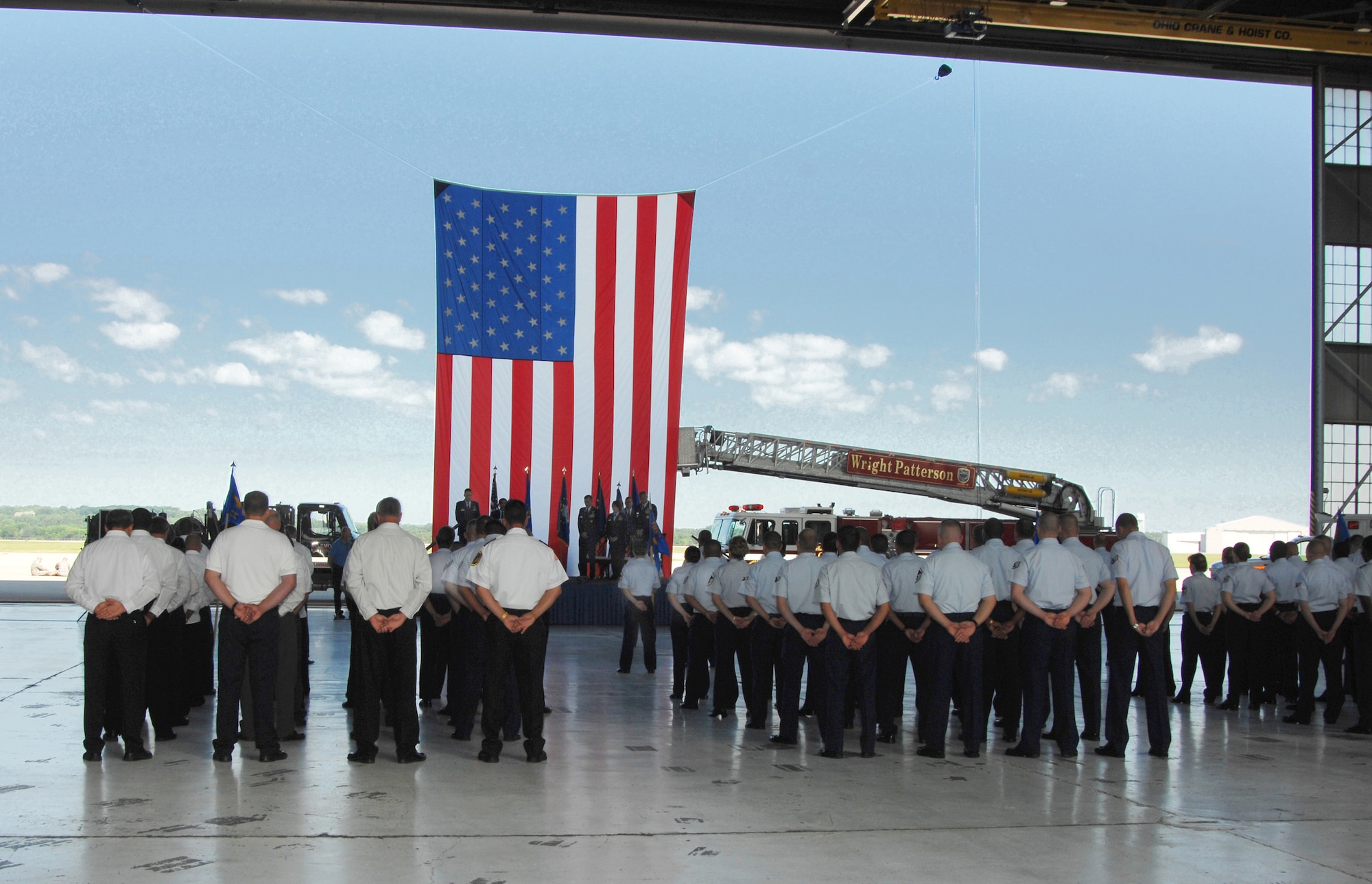 A formation of 88th Air Base Wing Airmen and civilian employees and equipment frame the site of the Wing change of command ceremony at Wright-Patterson Air Force Base, Ohio.  Colonel Bradley D. Spacy succeeded Col. Colleen Ryan during the July 14 event which took place in a historic World War Two-era hangar adjacent to the base flightline. Lt. Gen. Jack Hudson, commander of the Aeronautical Systems Center, presided. (U.S. Air Force photo/Ben Strasser).