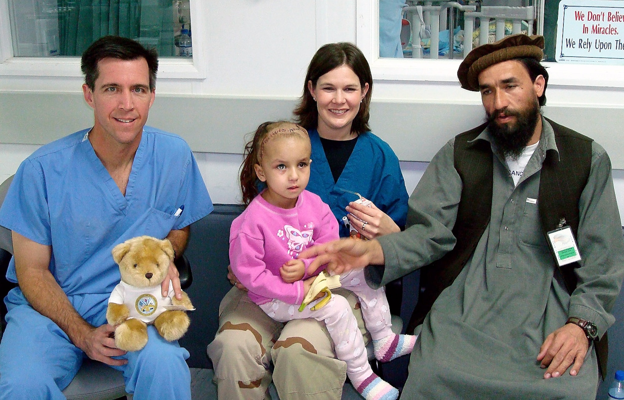 Lt. Col. (Dr.) Randall McCafferty, a neurosurgeon deployed from Lackland Air Force Base, Texas (left); and Capt. Stacy Friesen, a neonatal intensive care nurse deployed from Travis Air Force Base, Calif.; visit with Zahara and her father at the Craig Joint Theater Hospital, Afghanistan. Zahara was injured and received several surgeries at the hospital. (Courtesy photo)