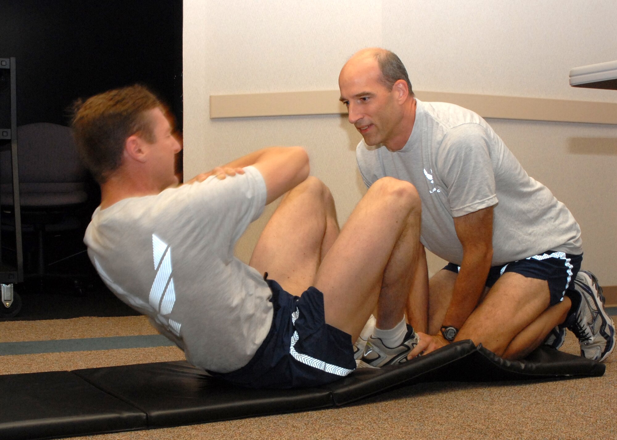 Air Force Reservist Col. Albert Reif (left), 940th Air Refueling Wing commander, does a crunch as part of his Air Force physical fitness test, as Col. Jeffrey "Sal" Mineo, commander of Detachment 2 and the future wing commander, holds his feet and counts the repetitions July 13, 2008 at Beale Air Force Base, Calif.; both colonels scored a perfect 100 percent on their tests.  Airmen must constantly hone their physical abilities to withstand and overcome the demanding rigors of deployment and combat. (U.S. Air Force photo/Stacey Knott)