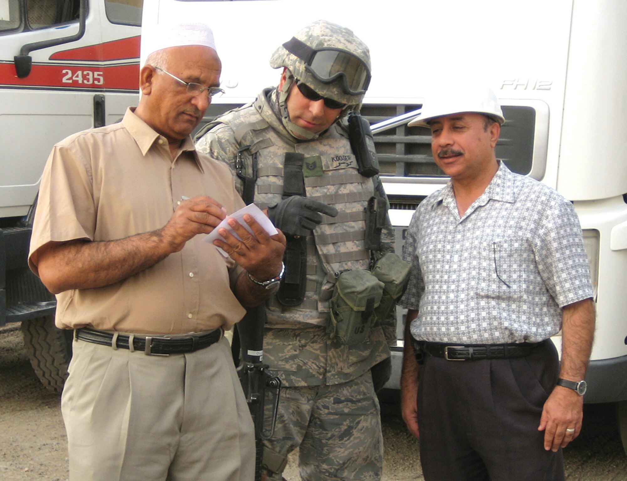 Tech. Sgt. Karl Kooser, a 163rd Logistics Readiness Squadron fuels craftsman, who is deployed and assigned to the 386th Expeditionary Security Forces Squadron in Southwest Asia, reviews documents with Gul Al-Hussani (left) and Mahmoud Suleman (right) at an undisclosed construction material site. (U.S. Air Force photo)