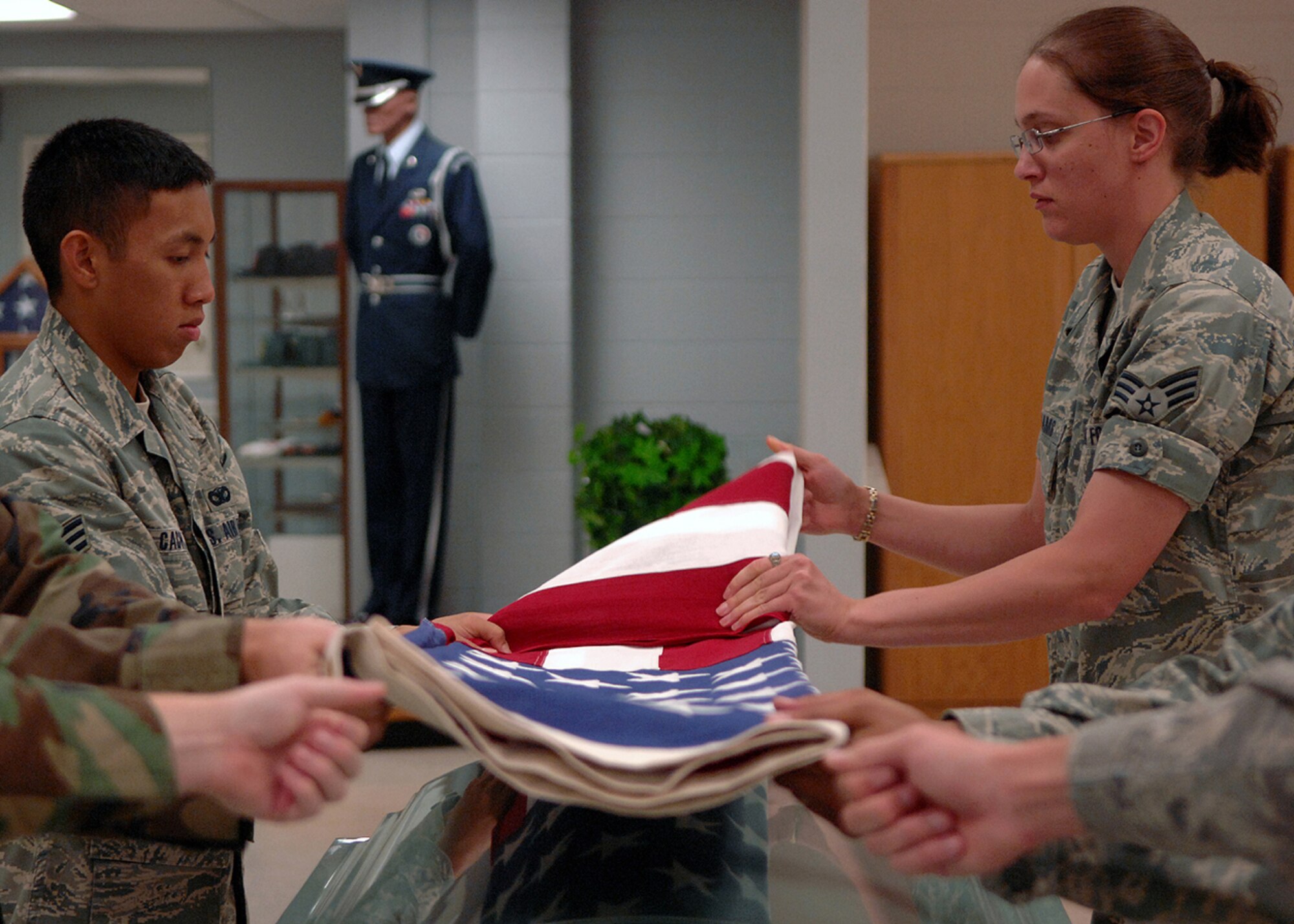 MOODY AIR FORCE BASE, Ga. – Senior Airman Stephanie Williams, 23rd wing Public Affairs Graphics Journeyman and Senior Airman Nester Cacho, 822nd security Forces Squadron fold the flag as other members of the base's Honor Guard hold the ends to stop it from creasing during practice here July 10. (U.S. Air Force photo by Airman Joshua A. Green)

