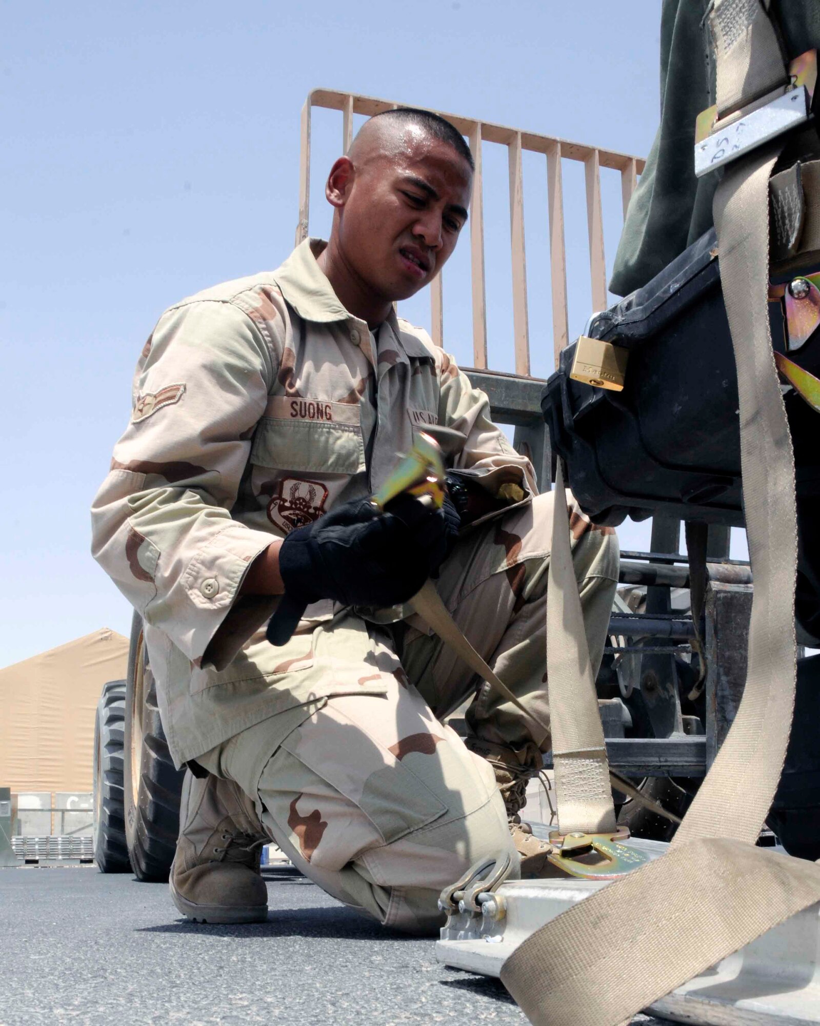SOUTHWEST ASIA -- Airman 1st Class Veasna Suong, 8th Expeditionary Air Mobility Squadron air transportation specialist, ties down palletized cargo in preparation for transportation July 8. Last year, 8 EAMS transported 270,000 passengers and 94,000 tons of cargo. (U.S Air Force photo/SeniorAirman Domonique Simmons)