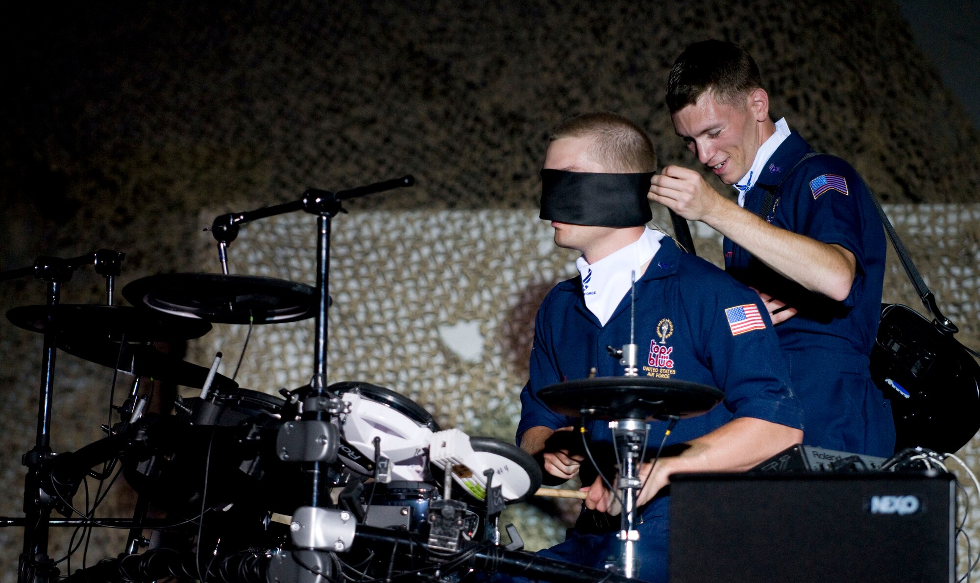 BAGRAM AIR FIELD, Afghanistan -- Senior Airman David Leatherwood, guitarist for Tops in Blue, blindfolds drummer Airman 1st Class Jaron Seuis during his drum solo here on July 13, 2008. Airman Seuis proceeded to showcase is drumming talent by continuing the solo blind. Airman Seuis is an aerospace propulsion journeyman for the 116th Maintenance Squadron, Robins Air Force Base, Ga., and hails from Ocala, Fla. (U.S. Air Force photo by Staff Sgt. Samuel Morse)