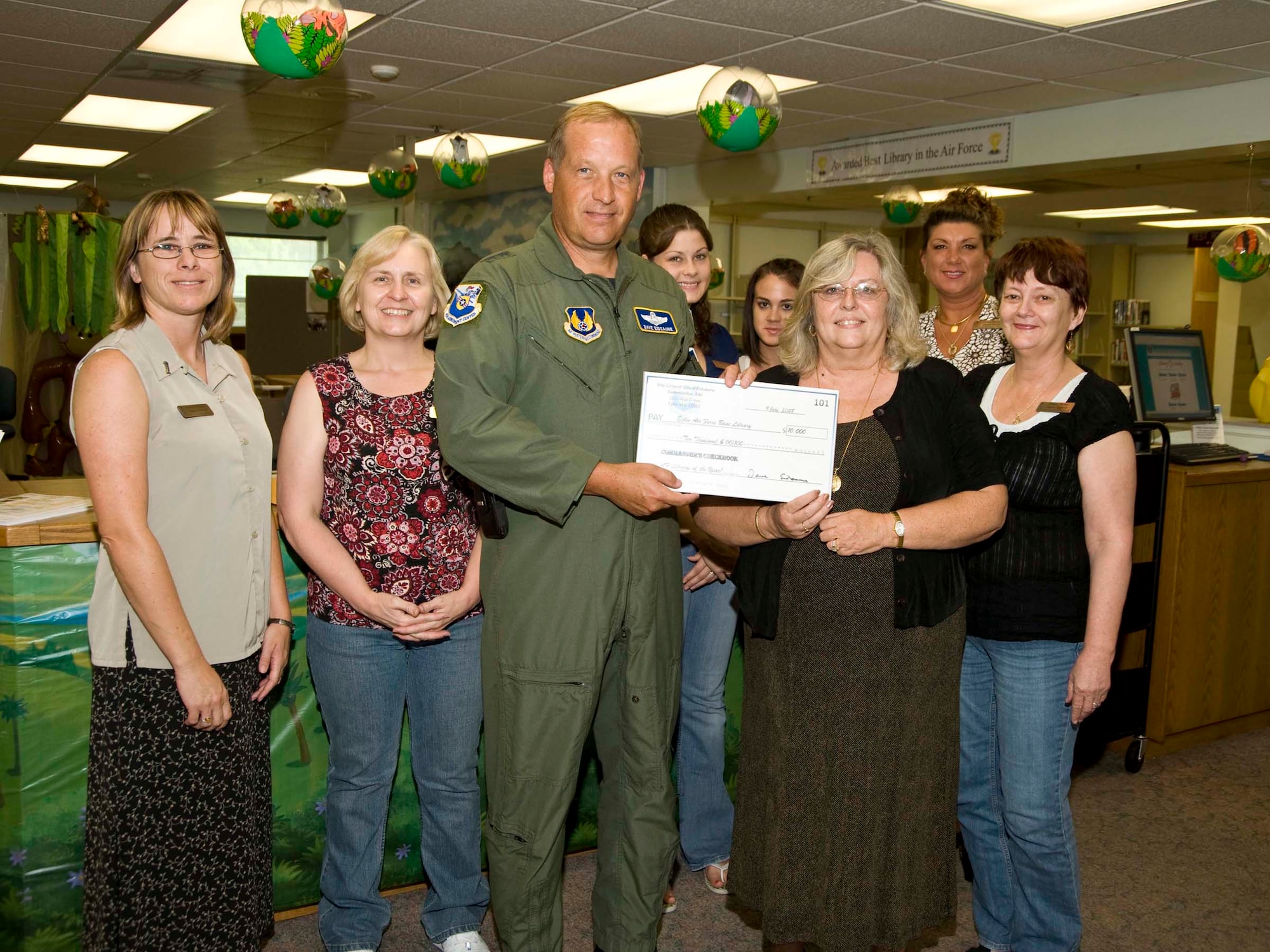 Maj. Gen. David Eidsaune, program executive officer for weapons and AAC commander, presents a $10,000 check to Donna Holovack and the library staff as part of his quality-of-life improvements. The library plans to use the money to upgrade its resources. The general also coined Ms. Holovack to recognize the library's selection as best in the Air Force. (USAF photo by Bruce Hoffman)