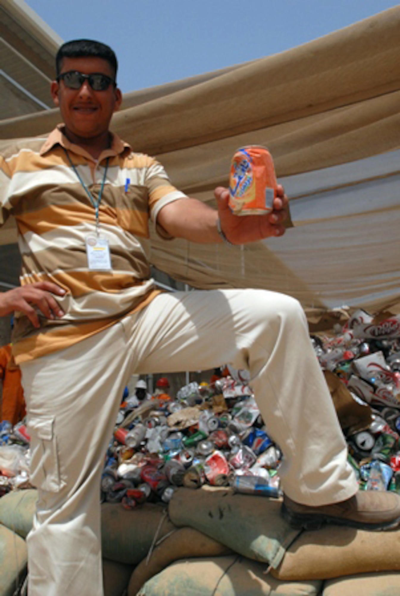 JOINT BASE BALAD, Iraq -- Naseb Saad Hasan Altememy holds up a can of future profits for his recycling center at a refuse collection site here July 7. The recycling center, which will provide jobs to local Iraqis, will assist current efforts to sort through daily garbage collection on post for recyclables. The recyclables will then be shipped off post and sold for profit on the Iraqi market. Mr. Altememy is the general manager for Almandhour United Co. (U.S. Army photo/Sgt. Robert G. Cooper III)