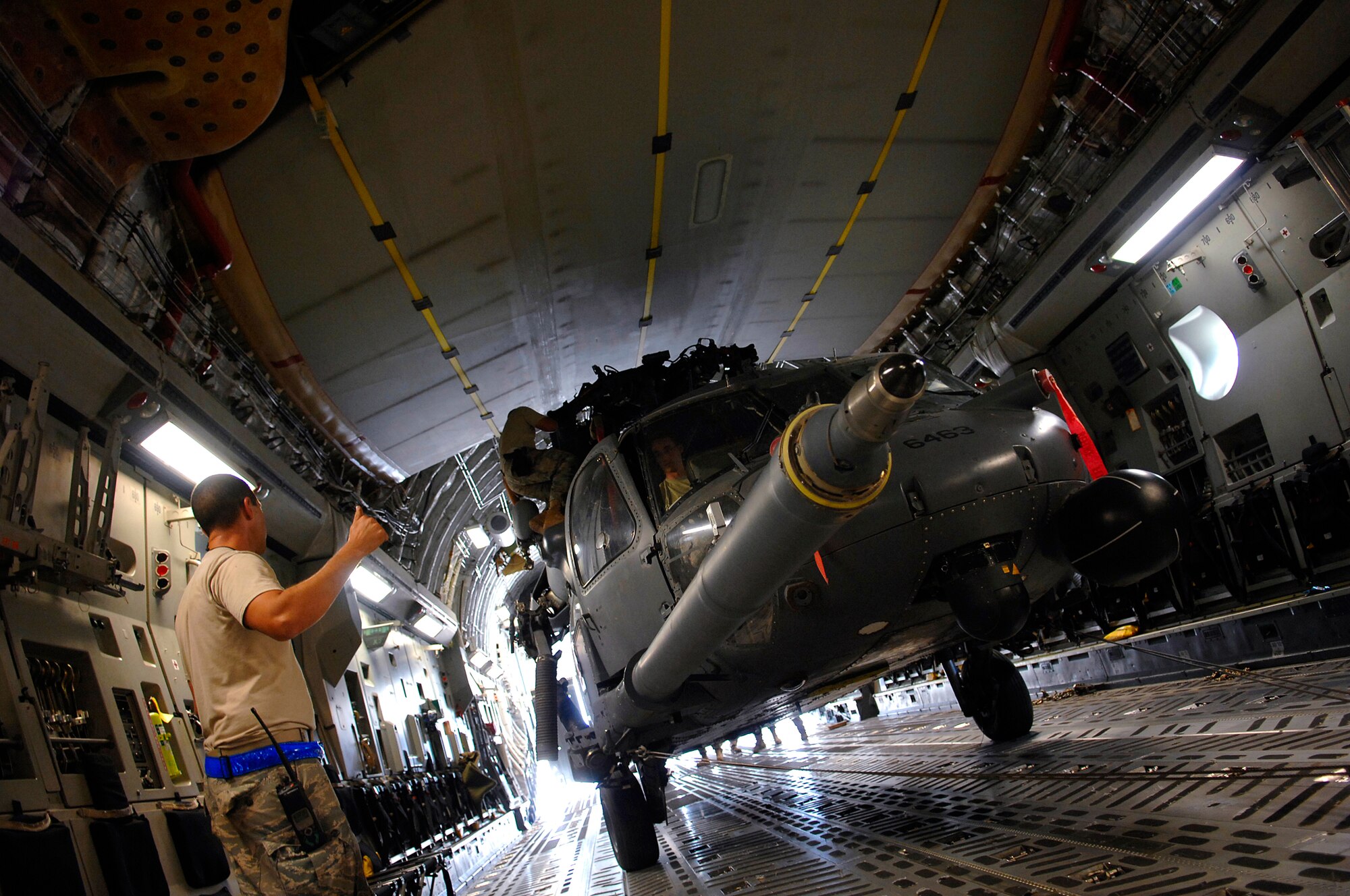 JOINT BASE BALAD, Iraq -- Tech. Sgt. Joseph Herrera, 64th Expeditionary Helicopter Maintenance Unit crew chief, gives a thumbs up to loadmasters during an upload of an HH-60 Pave Hawk into a C-17 Globemaster III here July 12. The helicopter is configured in a folded position that allows it to be loaded with enough clearance all around. Sergeant Herrera is deployed from Davis-Monthan Air Force Base, Ariz. (U.S. Air Force photo/Senior Airman Julianne Showalter)