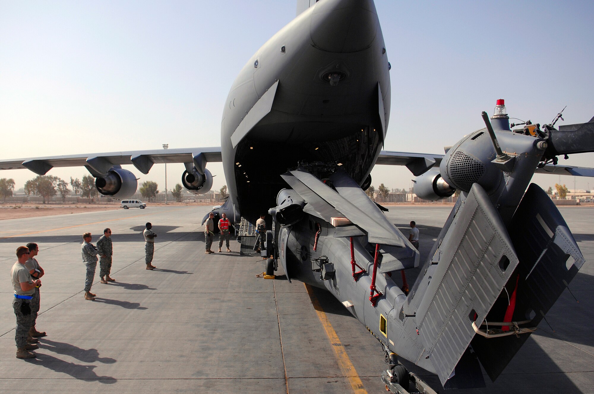 JOINT BASE BALAD, Iraq -- A team of Airmen assigned to the 64th Expeditionary Helicopter Maintenance Unit, stand in position around an HH-60 Pave Hawk during upload into a C-17 Globemaster III here July 12. The Airmen position themselves 360 degrees around the helicopter to ensure it will not make contact with the aircraft. The Airmen assigned are deployed from Davis-Monthan Air Force Base, Ariz. (U.S. Air Force photo/Senior Airman Julianne Showalter)