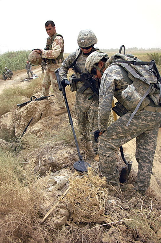 U.S. Army Sgt. Edwin Gonzalez and Pvt. Alfredo Delpozo, search for hidden weapon caches using a metal detecor in Hor Al Bosh, Iraq, July 2, 2008. Gonzalez and Delpozo are assigned to the 66th Engineers Company, 25th Infantry Division, which is working with Iraqi soldiers to find enemy weapons caches.