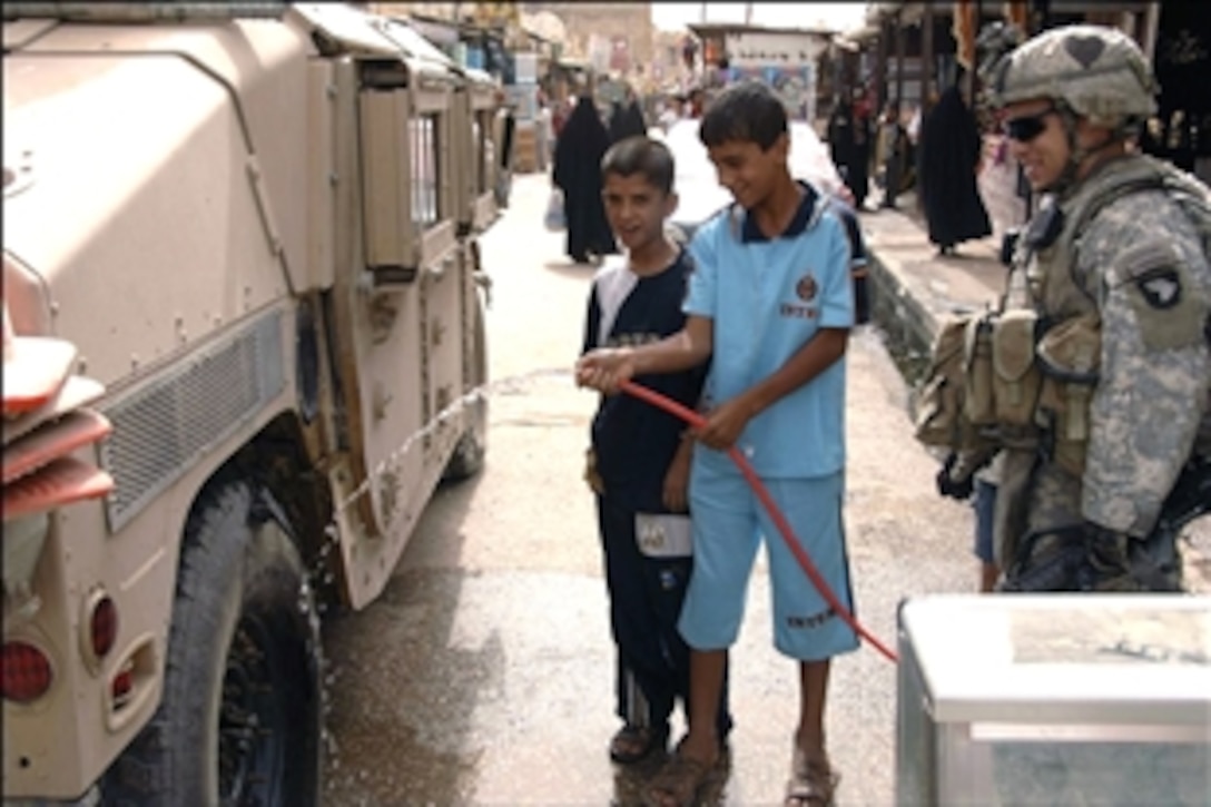 U.S. Army Sgt. Fabian Reyes lets local Iraqi boys have some fun by helping him wash his Humvee during a patrol through the central market in the Shula district, Baghdad, Iraq, July 9, 2008. Reyes is assigned to the 101st Airborne Division's Troop B, 1st Squadron, 75th Cavalry Regiment. 