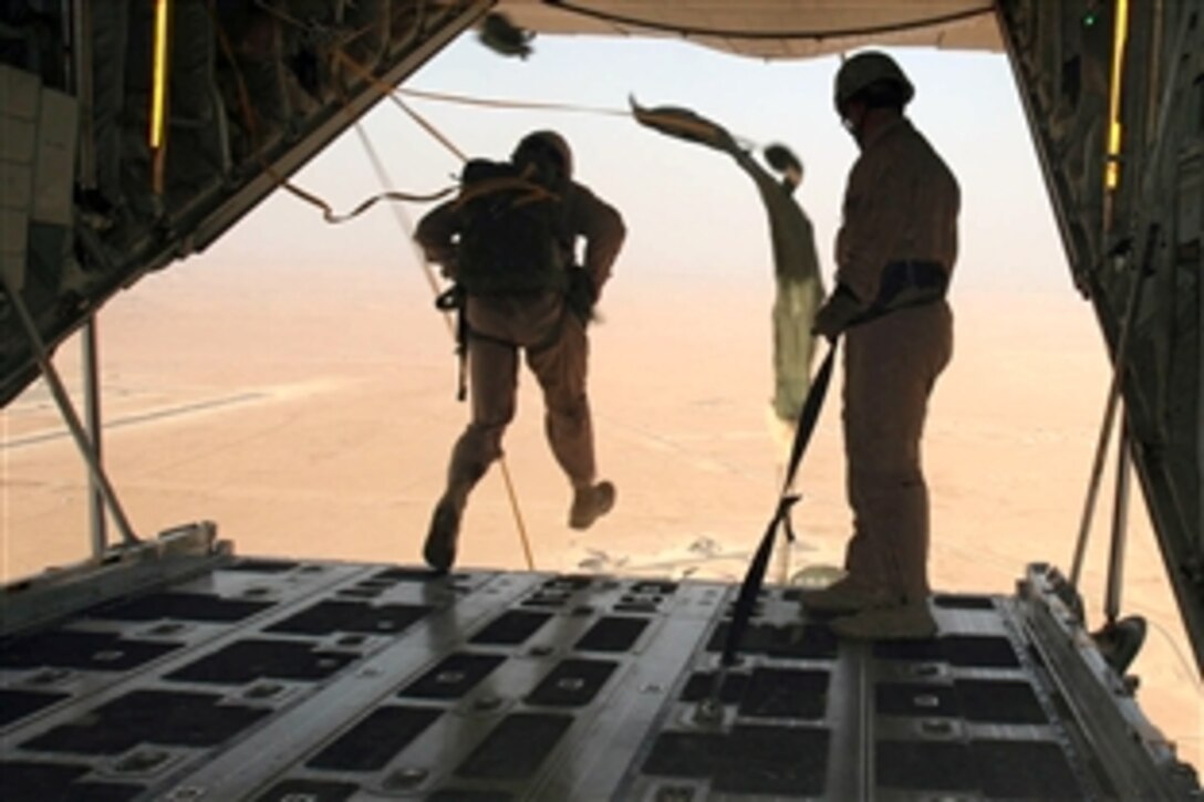 The last U.S. Marine assigned to Echo Company, 3rd Reconnaissance Battalion, Regimental Combat Team 1, exits the KC-130J as a jumpmaster looks on ensuring the parachutes deploy properly over Twentynine Palms, Calif., July 3, 2008. 