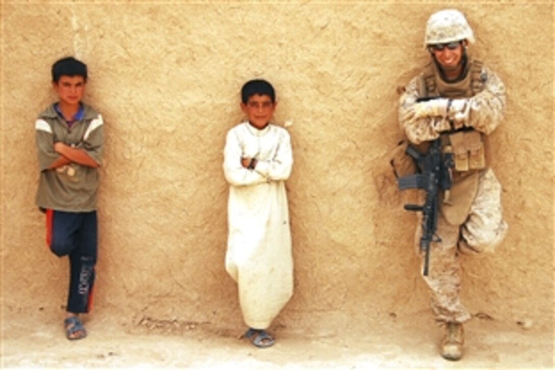 U.S. Marine Corps Cpl. Johathan R. Segovia, personnel security detail, 1st Marine Expeditionary Force, a ground combat element attached to Multinational Force - West, relaxes with Iraqi children in Sha-ban, Iraq, July 9, 2008. 