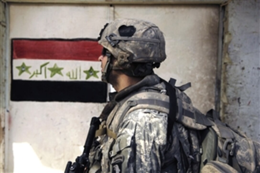 U.S. Army Spc. Dale Beaubien walks past a building with an Iraqi flag during a foot patrol in Shula, Iraq, July 7, 2008. Beaubien is assigned to the 1st Battalion, 502nd Infantry Regiment, 101st Infantry Division. 