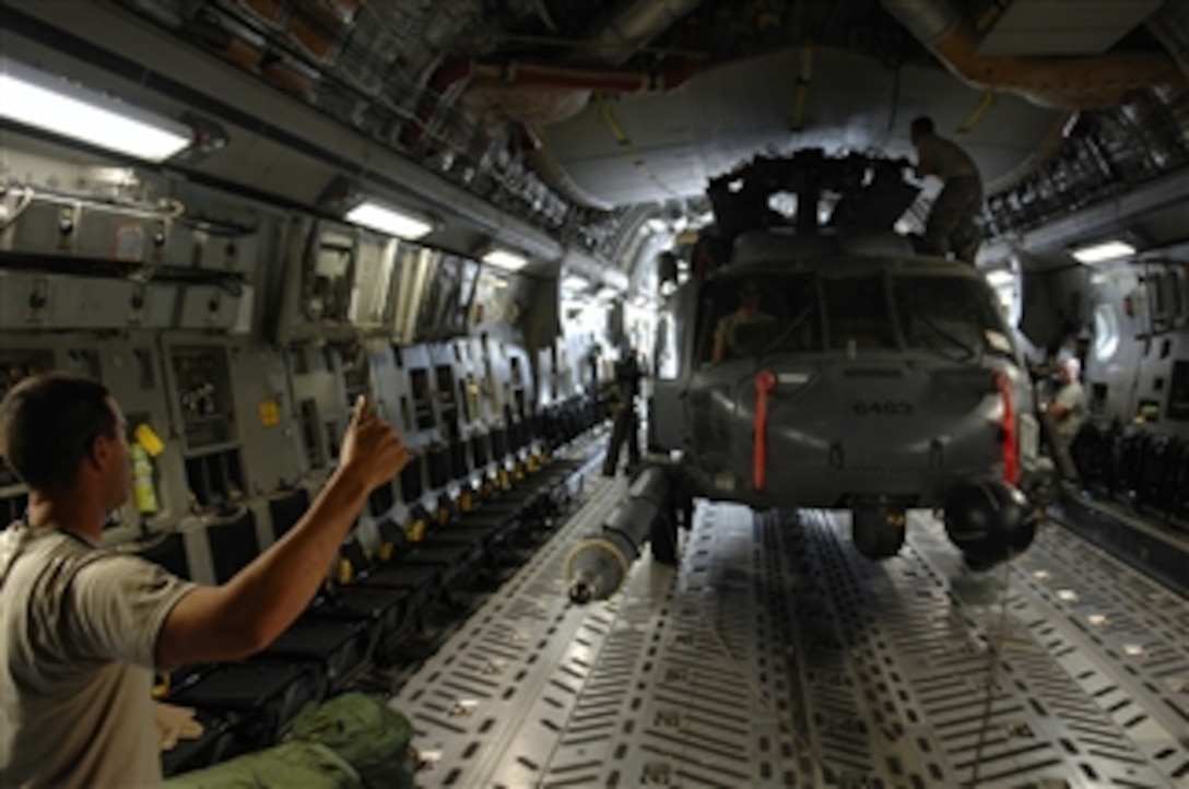 U.S. Air Force Tech. Sgt. Joseph Herrera, a crew chief with the 64th Expeditionary Helicopter Maintenance Unit, signals other crew chiefs and loadmasters as a winch system drags an HH-60 Pave Hawk helicopter onto a C-17 Globemaster III aircraft at Joint Base Balad, Iraq, on July 12, 2008.  Herrera is deployed from Davis-Monthan Air Force Base, Ariz.  