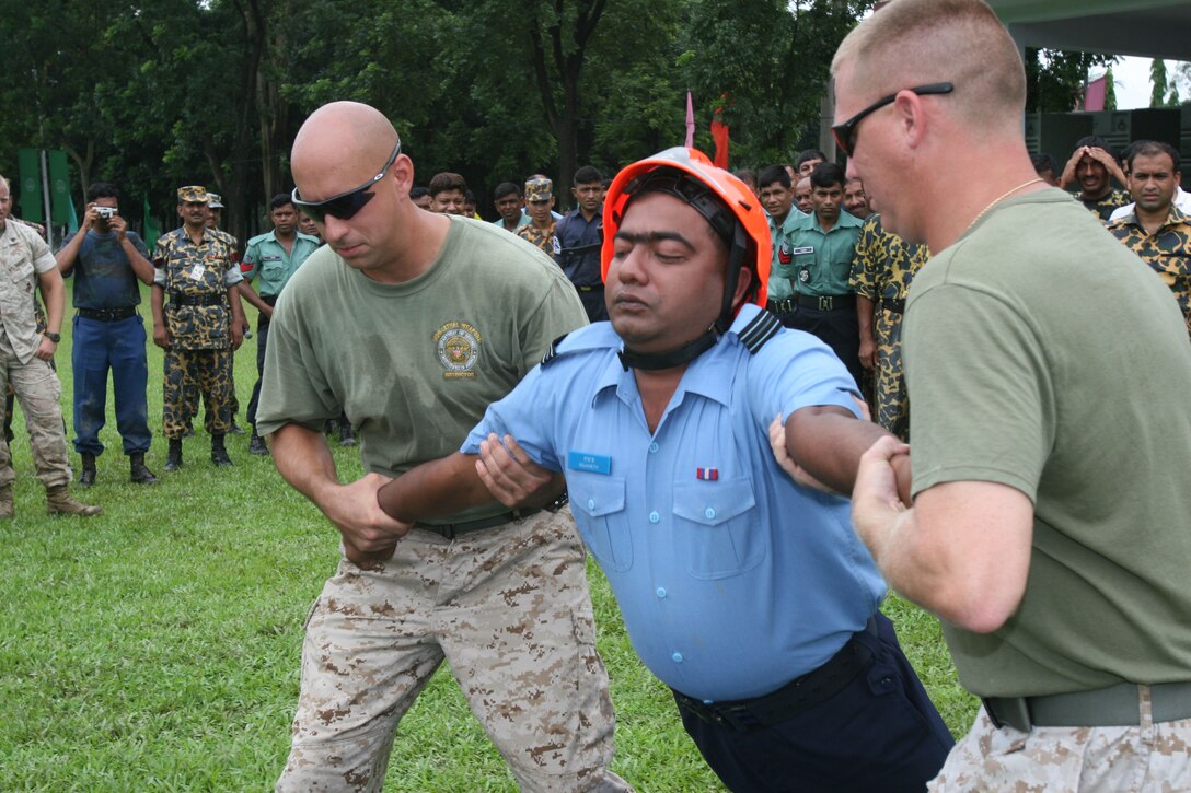 Marine instructors ease Bangladesh Air Force Flight Lt. Muzaffor Raahath to the ground while experiancing the effects of a X26E electro-muscular disrupter (stun gun)  July 15 during Non-Lethal Weapons Executive Seminar 2008 here.