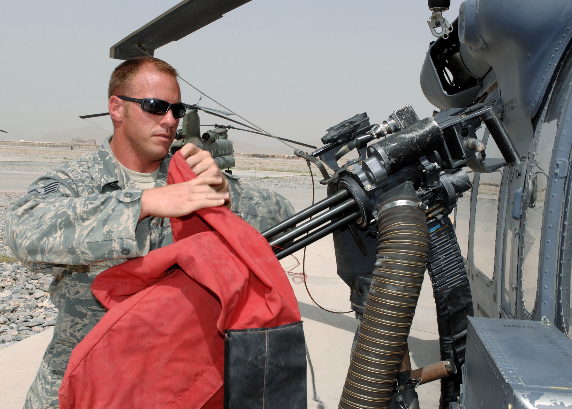 Staff Sgt. Ernest Kunde removes the dust cover off the gun of a HH-60G Pave Hawk before an alert mission at Kandahar Air Field, Afghanistan. Sergeant Kunde is a 305th Expeditionary Rescue Squadron HH-60G Pave Hawk crew chief. (U.S. Air Force photo/Master Sgt. Demetrius Lester)
