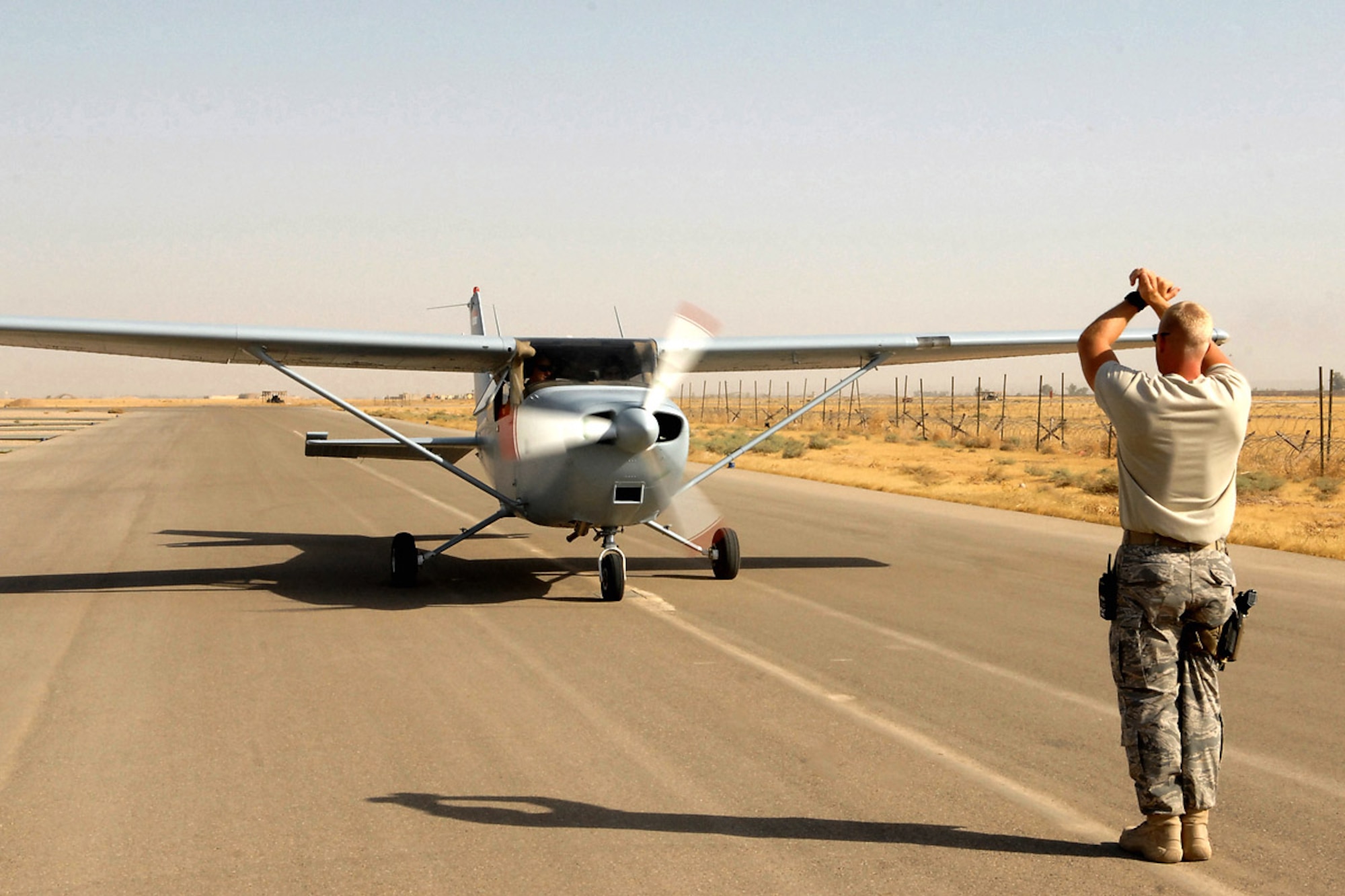 Staff Sgt. Kevin Bremmer marshals a Cessna 172 July 13 at Kirkuk Regional Air Base, Iraq.  The aircraft was flown by 2nd Lt. "Joseph," an Iraqi air force student pilot, and Capt. Jamie Riddle, a 52nd Expeditionary Flying Training Squadron instructor pilot. The pilots surpassed 2,000 flight training hours, marking a milestone for the Iraqi air force.  Sergeant Bremmer is deployed to the 52nd EFTS from McGuire Air Force Base, N.J., and Captain Riddle is deployed from Columbus AFB, Miss.  (U.S. Air Force photo/Airman First Class Randi Flaugh) 