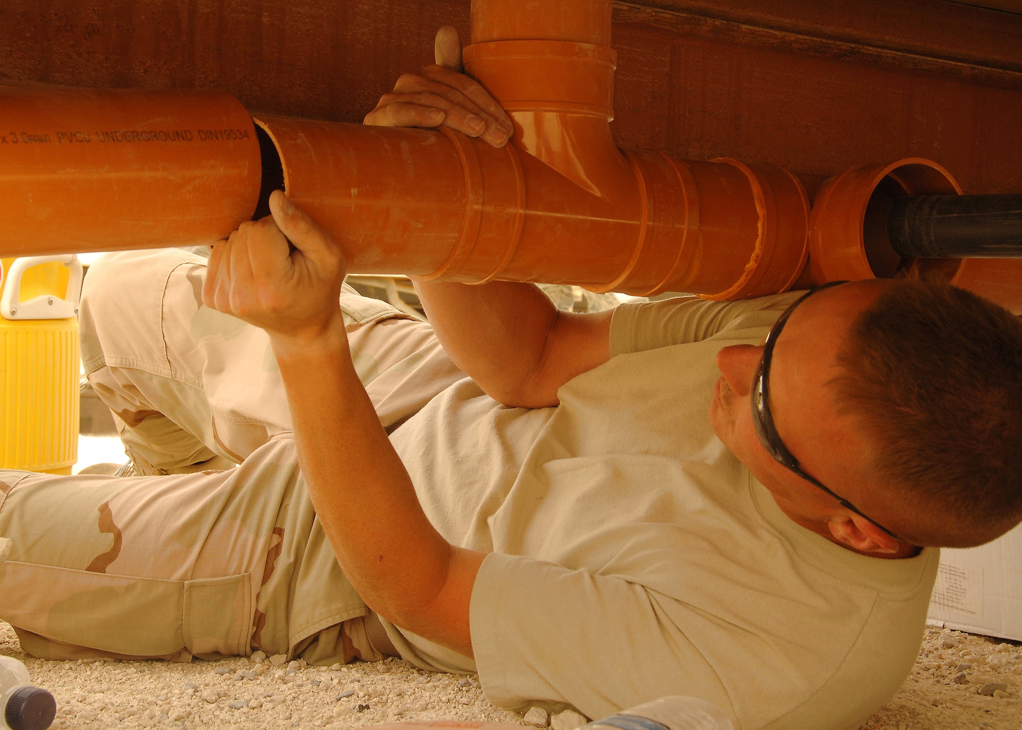 Tech. Sgt. Michael Biggs, a member of the 386th Expeditionary Civil Engineer Squadron, installs a PVC pipe under a new K-9 kennel on July 11 at a base in Southwest Asia. The 386th Expeditionary Civil Engineer Squadron is completing a project to increase the square footage of the K-9 kennels for the 386th Expeditionary Security Forces Squadron. Sergeant Biggs is deployed from the 108th Air Refueling Wing, McGuire Air Force Base, N.J. (U.S. Air Force photo/Tech. Sgt. Raheem Moore)