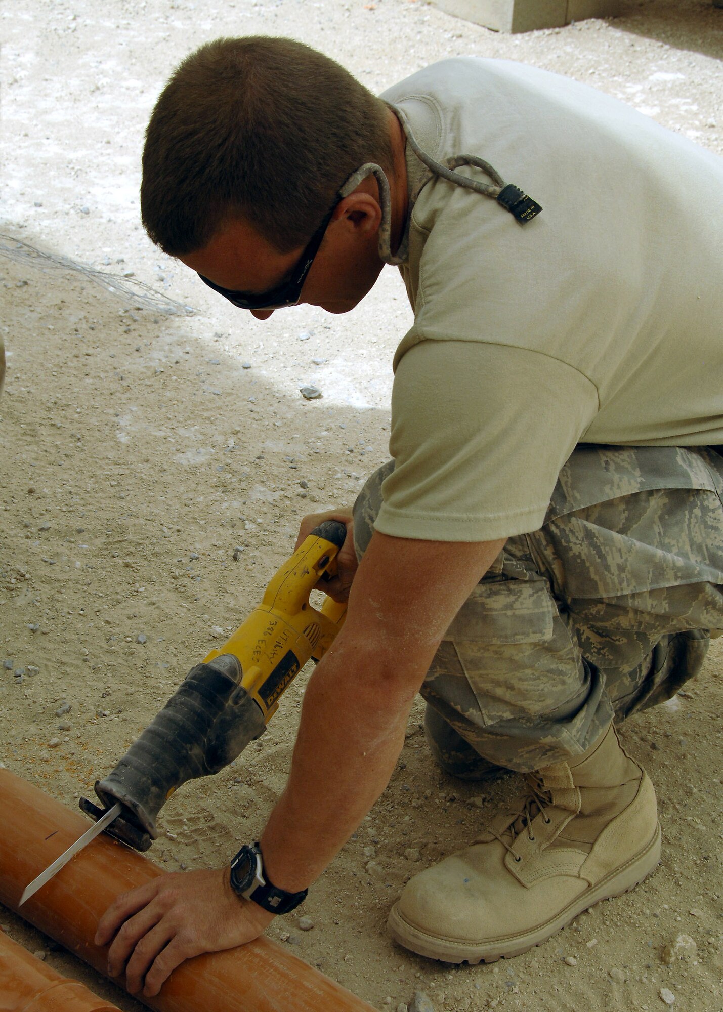 Senior Airman Mike Hughes, deployed to the 386th Expeditionary Civil Engineer Squadron, cuts a PVC pipe during construction on a new K-9 kennel on July 11 at a base in Southwest Asia. The 386th Expeditionary Civil Engineer Squadron is completing a project to increase the square footage of the K-9 kennels for the 386th Expeditionary Security Forces Squadron. Airman Hughes is deployed from the 169th Fighter Wing, McEntire Joint National Guard Base, S.C. (U.S. Air Force photo/Tech. Sgt. Raheem Moore)
