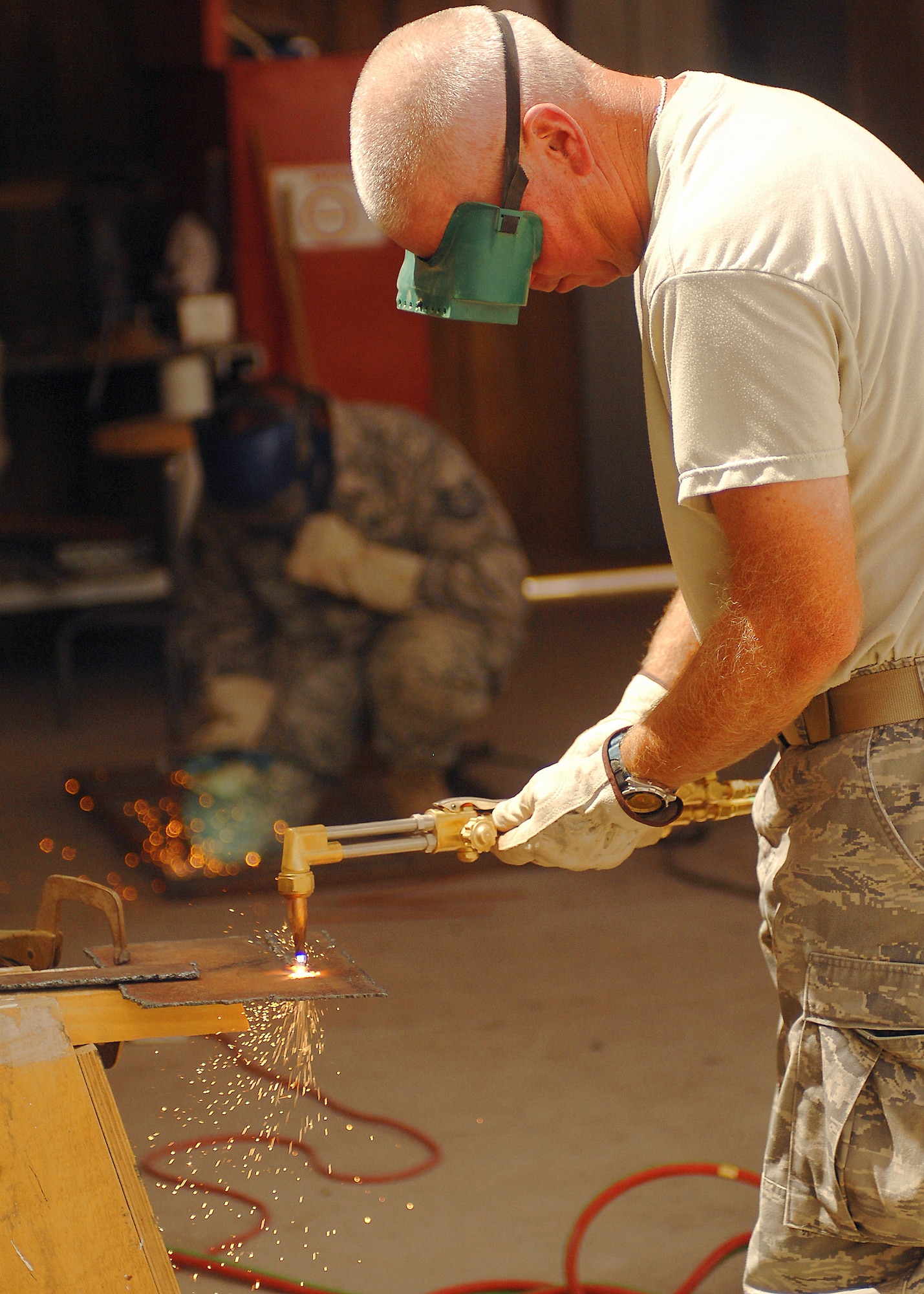 Staff Sgt. Mark Gorton (foreground) uses a blow torch to cut metal, while Tech. Sgt. Anthony Roman welds a frame together on July 11 at a base in Southwest Asia. The 386th Expeditionary Civil Engineer Squadron is completing a project to increase the square footage of the K-9 kennels for the 386th Expeditionary Security Forces Squadron. The metal frames will be used to build new ramps for the dogs. Sergeant Roman is deployed from the 156th Airlift Wing, Muniz Air National Guard Base, Puerto Rico. Sergeant Gorton is deployed from the 136th Airlift Wing, Fort Worth, Texas. (U.S. Air Force photo/Tech. Sgt. Raheem Moore)