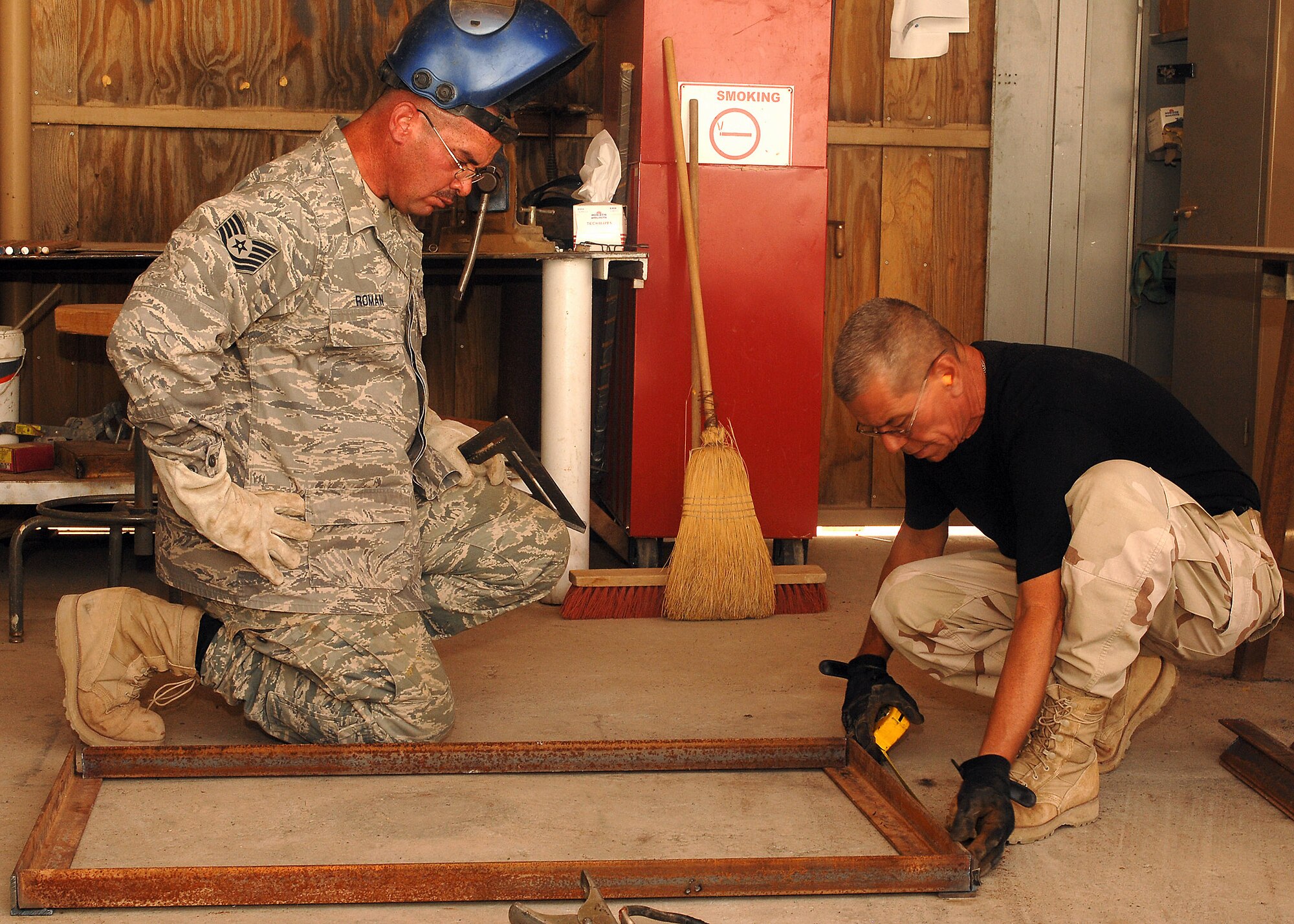 Master Sgt. Victor Collazo (right) and Tech. Sgt. Anthony Roman align and measure pieces of metal before they are welded together on July 11 at a base in Southwest Asia. The 386th Expeditionary Civil Engineer Squadron is completing a project to increase the square footage of the K-9 kennels for the 386th Expeditionary Security Forces Squadron. The metal frames will be used to build new ramps for the dogs. Sergeant Collazo and Sergeant Roman are deployed from the 156th Airlift Wing, Muniz Air National Guard Base, Puerto Rico. (U.S. Air Force photo/Tech. Sgt. Raheem Moore)