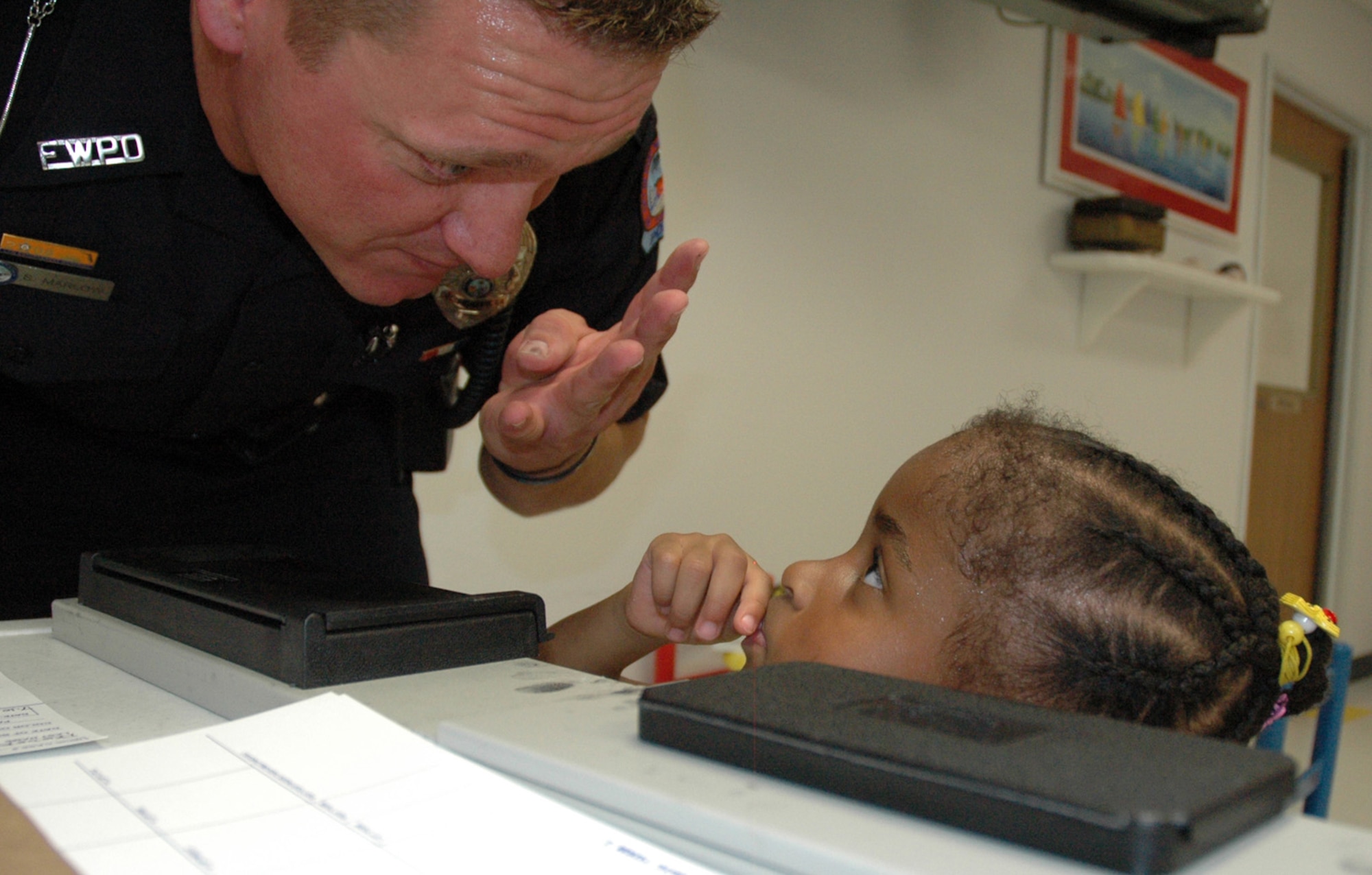 EGLIN AIR FORCE BASE, Fla. -- Officer Steven Marlow, Fort Walton Community Policing Officer, shows young Shameeka Ector how her fingerprints will be taken. The Child Abduction Safety Briefing held at Eglin's Child Development Center, modular CDC and the Youth Center July 10, provided parents the opportunity to both have their child fingerprinted for their personal keeping and learn ways they could prevent child abduction. (US Air Force photo by Airman 1st Class Anthony Jennings)