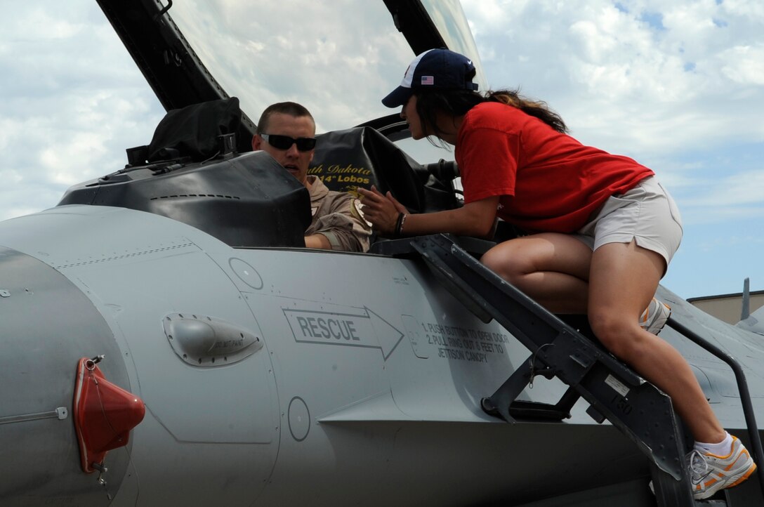 Capt. Scott Petz (left), Air National Guard 114th Fighter Wing pilot, gives Vicky Galindo (right), U.S.A. Olympic Softball Team second baseman, a closer look inside of an F-16 aircraft. The F-16 Fighting Falcon aircraft, B-1 Lancer aircraft, F-101 GE-102 engine, and a variety of missile systems were on display for the team to look at during their visit to Ellsworth, July 14. (U.S. Air Force photo/Senior Airman Kasey Zickmund)