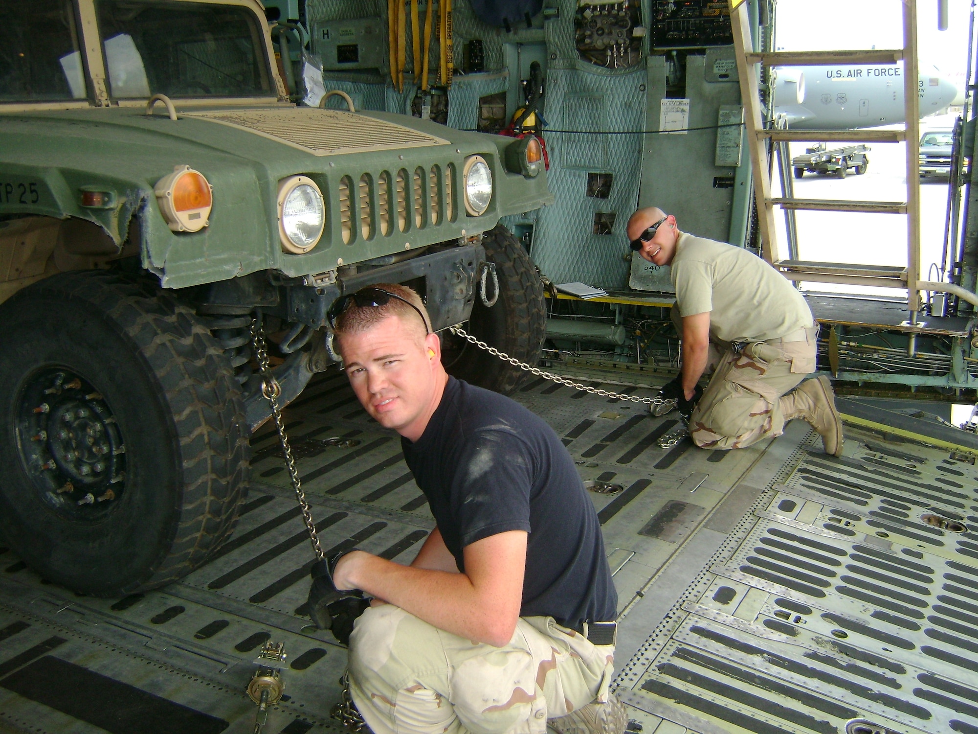Airman 1st Class Landon Jensen, 62nd Aerial Port Squadron left, and Staff Sgt. Marc Warman, an Airman deployed from Aviano Air Base, tie down a humvee for transport in a C-17 Globemaster III during a recent deployment to Manas Air Base, Kyrgyzstan.