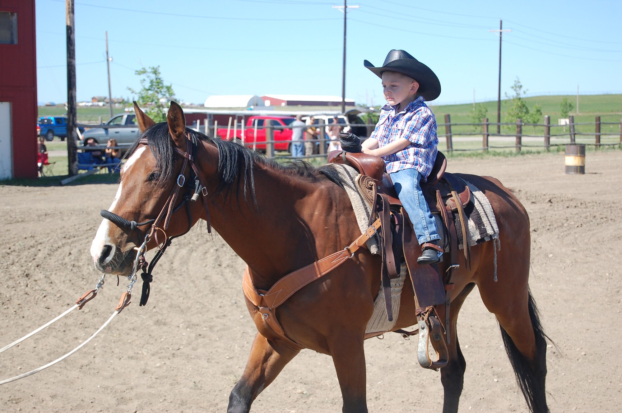 Little Warrior Logan, 4, on his parent's horse, Sarge, gets ready to perform with some assistance from his dad, who is leading the horse. Logan was the youngest competitor at the first Malmstrom Rider's Club rodeo July 12. (U.S. Air Force photo/Valerie Mullett)
