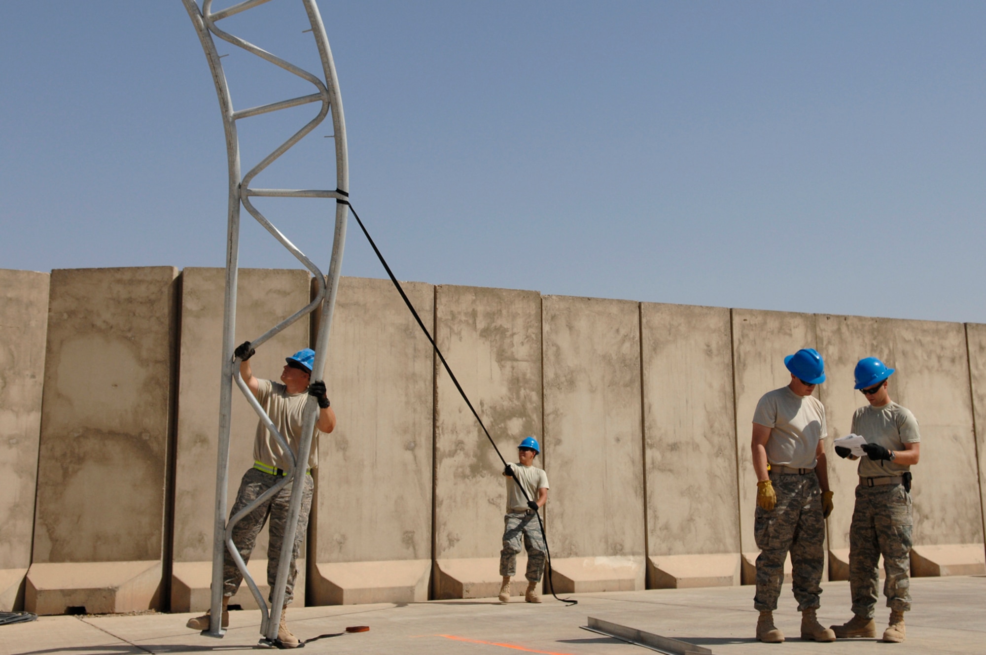JOINT BASE BALAD, Iraq -- Heavy equipment operators, or "Dirt Boyz," assigned to the 332nd Expeditionary Civil Engineer Squadron hold one of the arches for a sun shade in place here July 15 as they plan their next step. (U.S. Air Force photo/Senior Airman Julianne Showalter)
