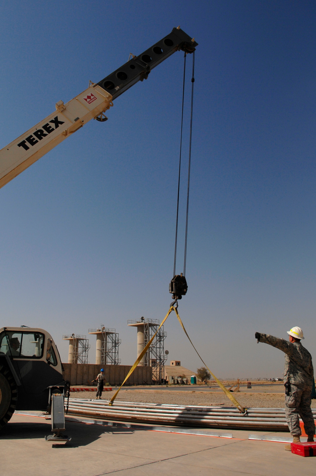 JOINT BASE BALAD, Iraq -- Master Sgt. Scott Austin, 332nd Expeditionary Civil Engineer Squadron "Dirt Boy," guides a crane as it lifts the skeletal structure of a sun shade here July 15. The sun shade will cover aircraft from the harsh Iraq sun. Sergeant Austin is deployed from Eielson Air Force Base, Alaska. (U.S. Air Force photo/Senior Airman Julianne Showalter)