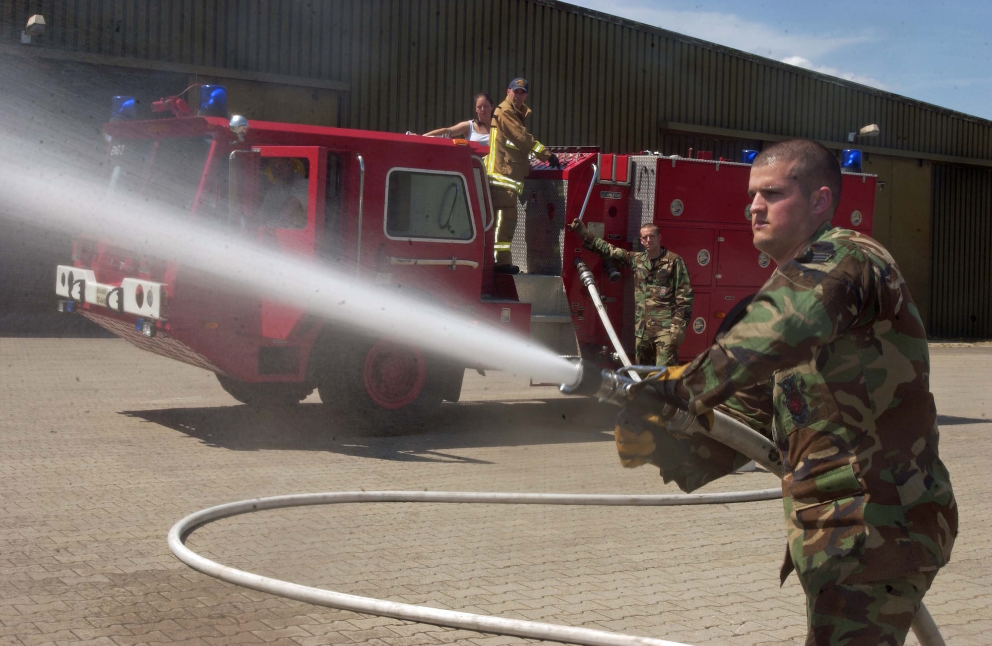 Airman 1st Class Taylor Hydrick, a firefighter with the 835th Civil Engineer Squadron, discharges the water from a fire hose of an AMERTEK Fire Truck July 10 on Rhine Ordnance Barracks. Photo by Christine June, USAG Kaiserslautern.                                          