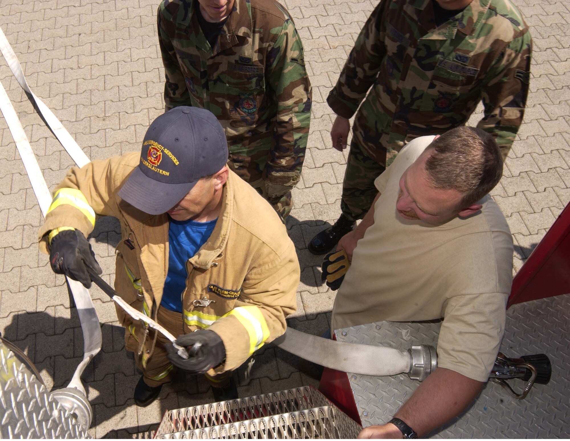 Olaf Klein-Chazkelewitz, a U.S. Army Garrison Kaiserslautern's fire inspector, explains to Airmen from the 835th Civil Engineer Squadron the correct use of the hose connector tool on an AMERTEK Fire Truck July 10 on Rhine Ordnance Barracks. Photo by Christine June, USAG Kaiserslautern.                                                                                                                                                                                                            