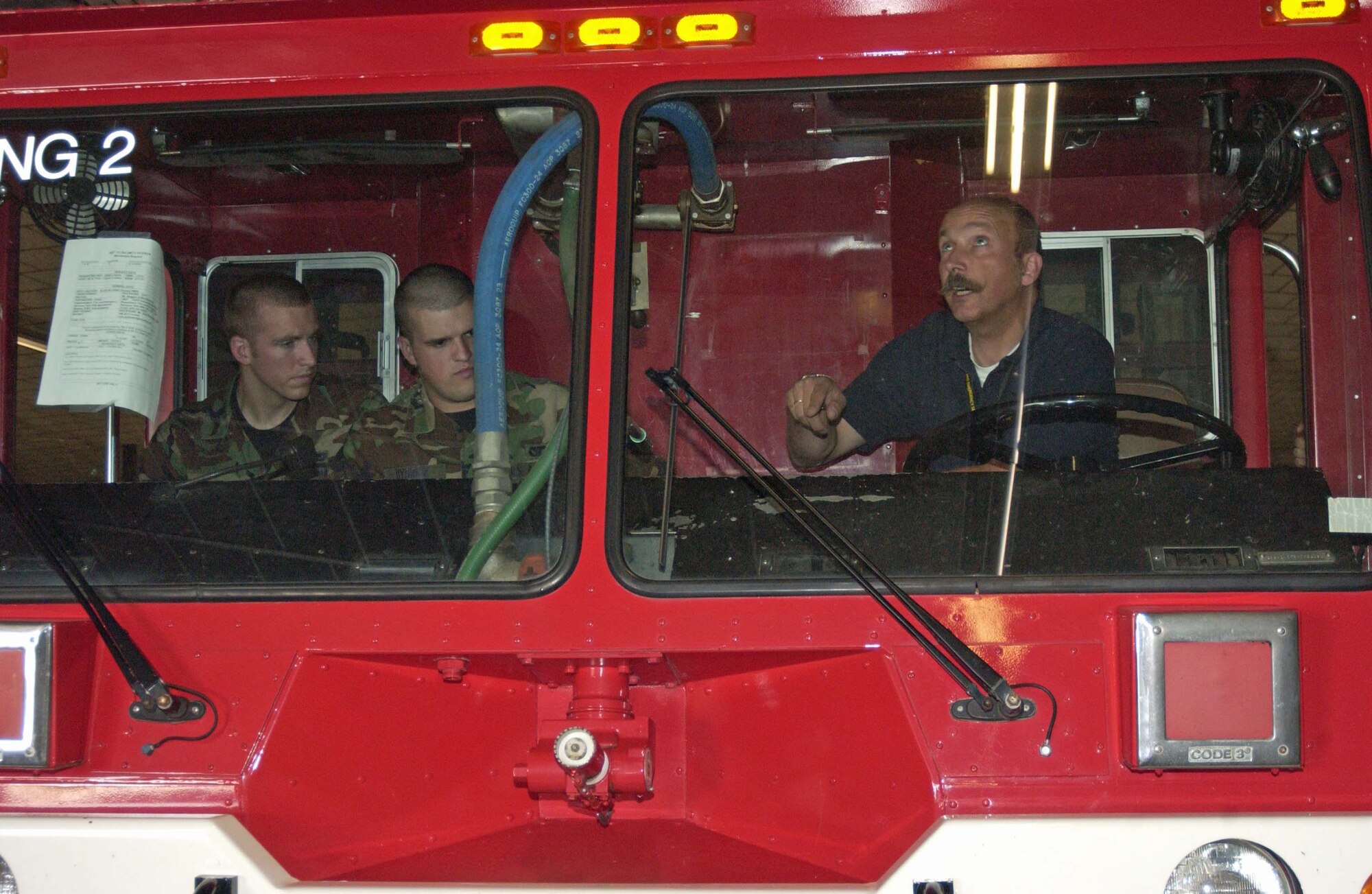 Klaus Kueppers, a U.S. Army Garrison Kaiserslautern fire inspector, shows Airmen from the 835th Civil Engineer Squadron (left) Airman Phil Samples and Airman 1st Class Taylor Hydrick the "pump-and-roll" (dispensing water while driving) method on an AMERTEK Fire Truck July 10 on Rhine Ordnance Barracks. Photo by Christine June, USAG Kaiserslautern.                               