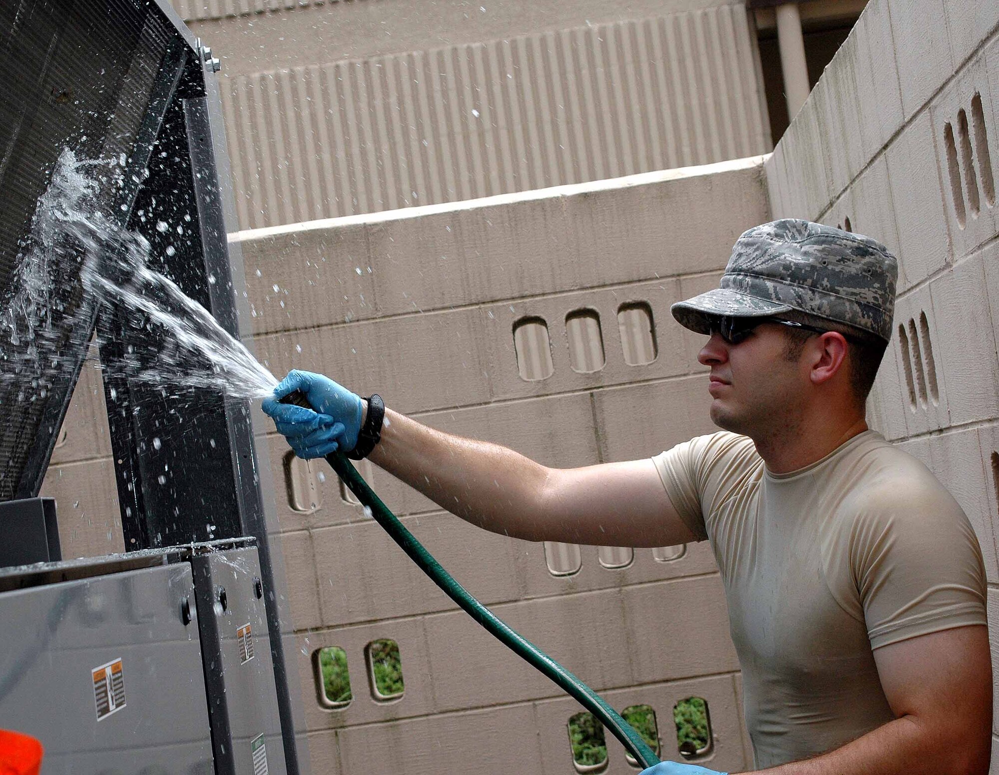 OSAN AIR BASE, Republic of Korea -- Staff Sgt. Chris Forgey, 51st Civil Engineer Squadron Heating, Ventilation, Air Conditioning and Refrigeration technician, sprays water onto a chiller unit to remove excess dirt and oil during a routine maintenance check. The 51st CES’ HVAC flight has been working 24 hours a day to complete repairs and routine inspections on all Team Osan air conditioning units. (U.S. Air Force photo/Staff Sgt. Candy Knight)