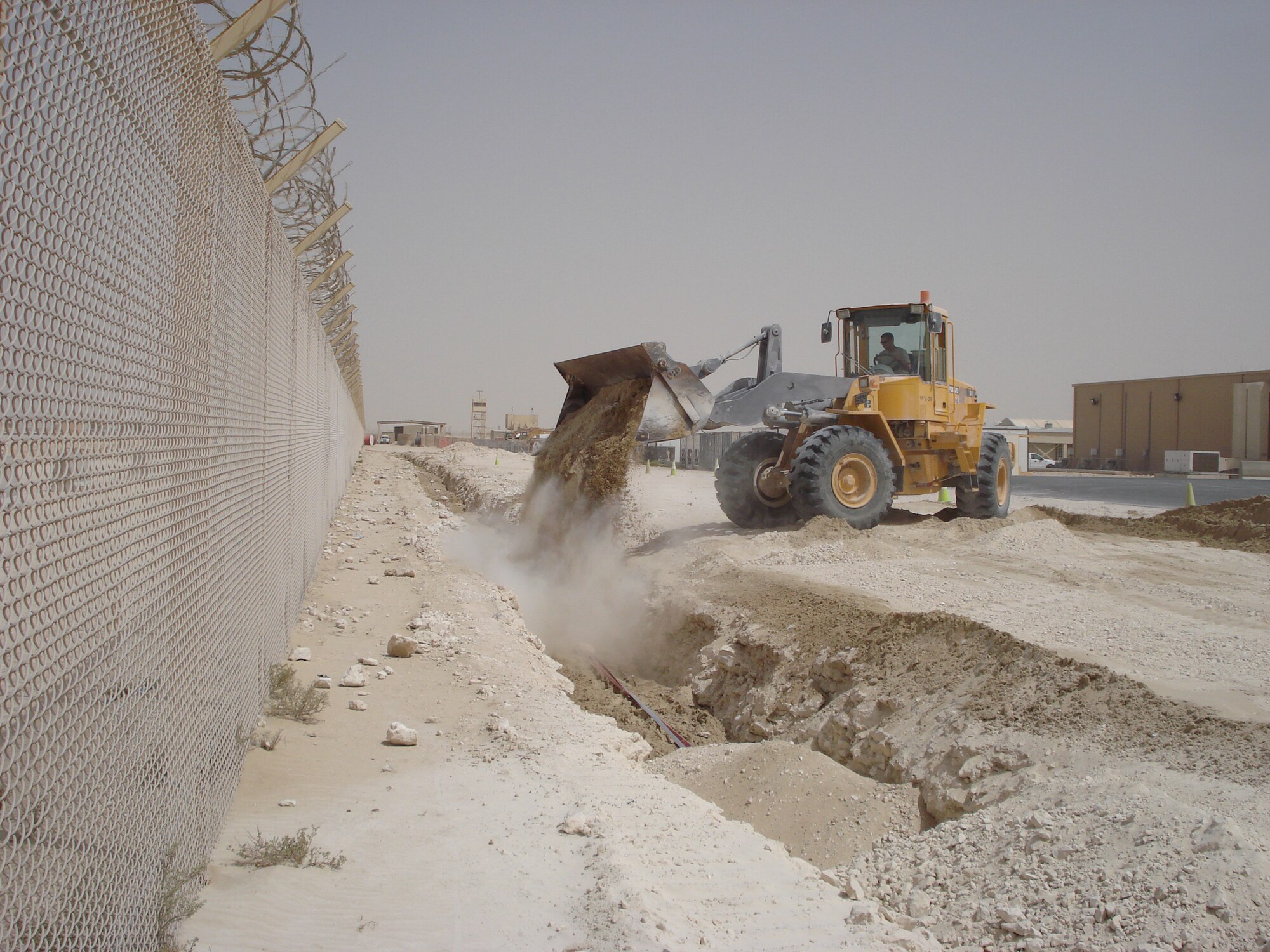 SOUTHWEST ASIA -- Airman 1st Class Joshua Mccathern, 379th Expeditionary Civil Engineering Squadron pavement and construction equipment journeyman, backfills a trench behind the Coalition Compound Dining Facility here April 16 with a front-end loader. The trench was for a high voltage electrical line. (U.S. Air Force photos by Staff Sgt. Shawn Berringer)
