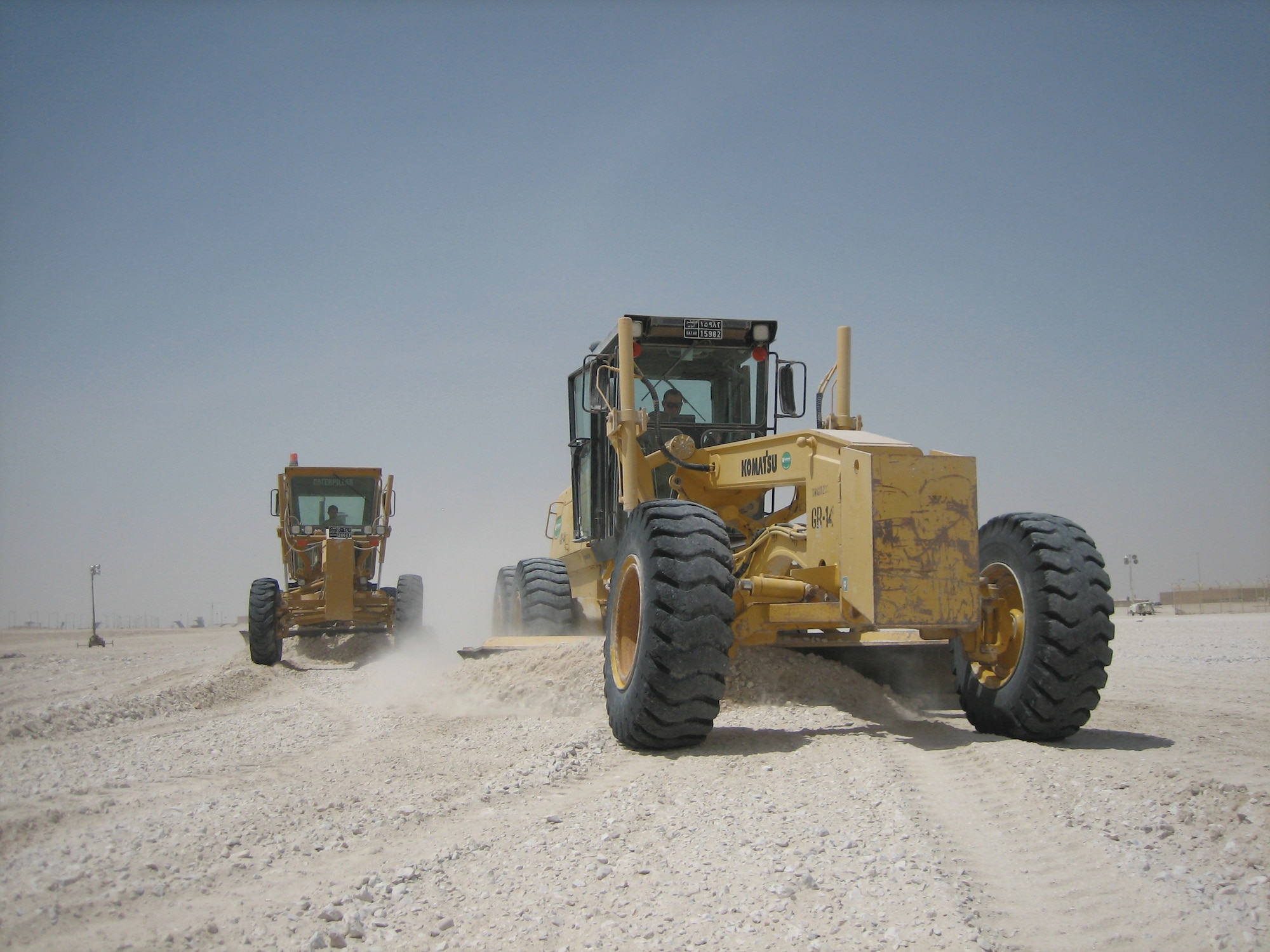 SOUTHWEST ASIA -- Tech. Sgt. Robert Lewis, left, and Staff Sgt. Ty Bun, 379th Expeditionary Civil Engineering Squadron pavement and construction equipment craftsmen, grade a parking lot near the new transportation building in the north ramp area here July 3. (U.S. Air Force photos by Staff Sgt. Shawn Berringer)