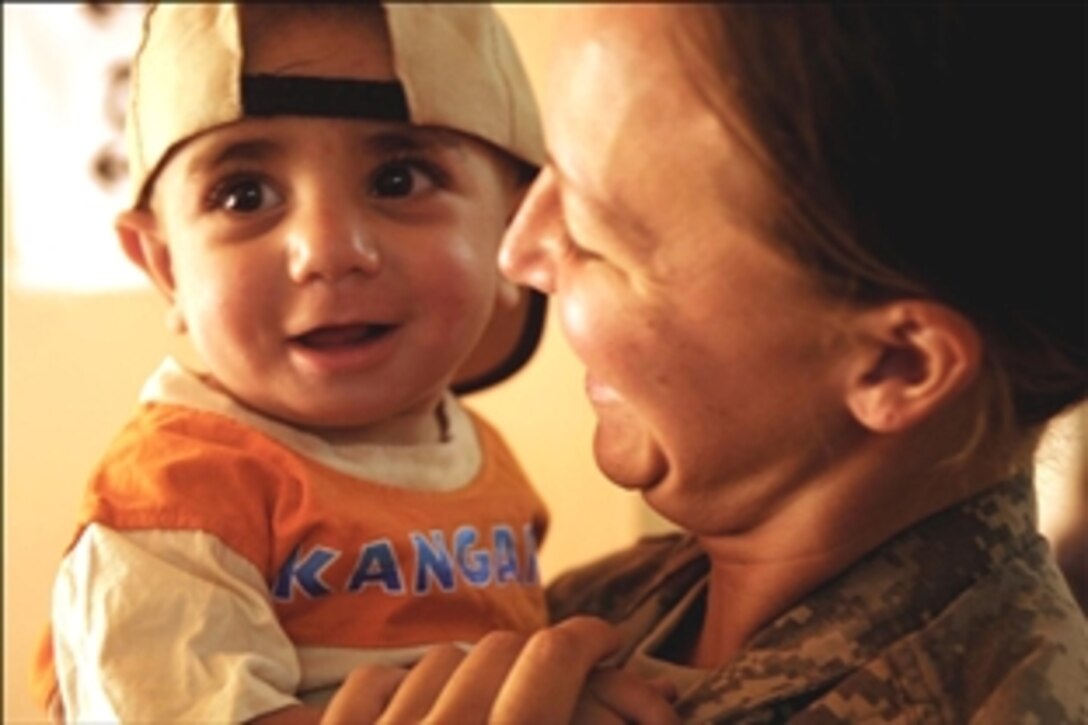 U.S. Army Staff Sgt. Kristy Vanlanen holds an Iraqi child at the Civil Military Operations Center at Forward Operating Base Hawk, Iraq, July 13, 2008. Vanlanen is assigned to the 432nd Civil Affairs Battalion, 4th Infantry Division. 
