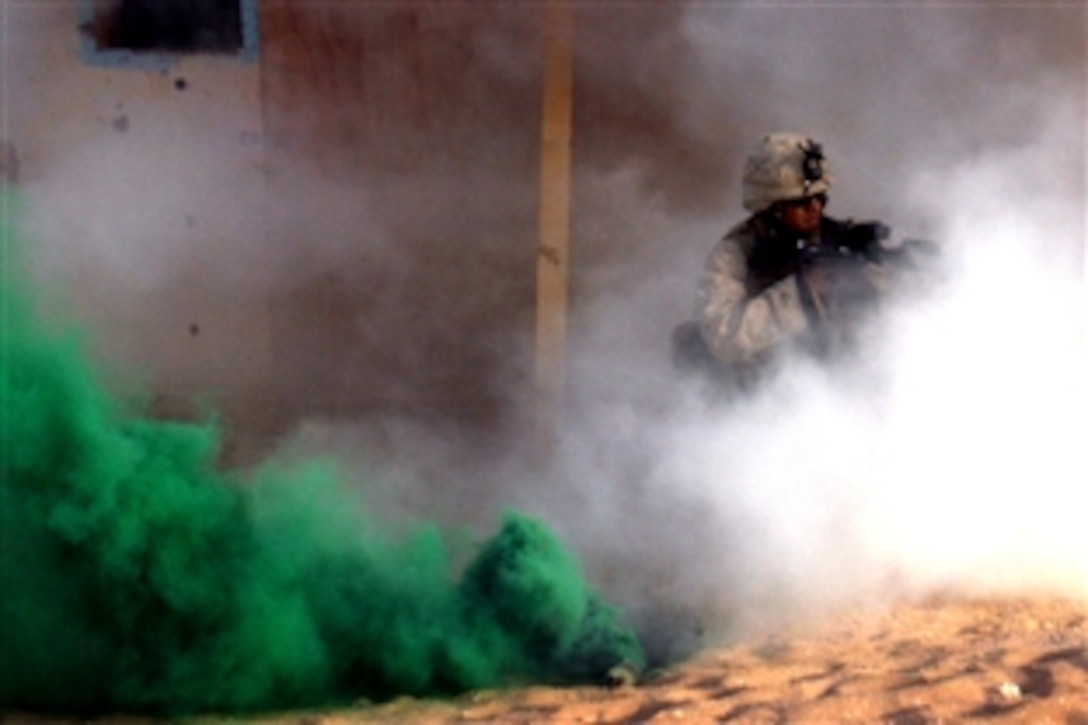 Marine Lance Cpl. Randy Aisen provides cover while concealed by smoke as fellow Marines place a breach charge during urban terrain training on Camp Buehring, Kuwait, July 8, 2008. Aisen is a light-armored vehicle scout assigned to the 15th Marine Expeditionary Unit's Weapons Company, 2nd Battalion, 5th Marine Regiment.