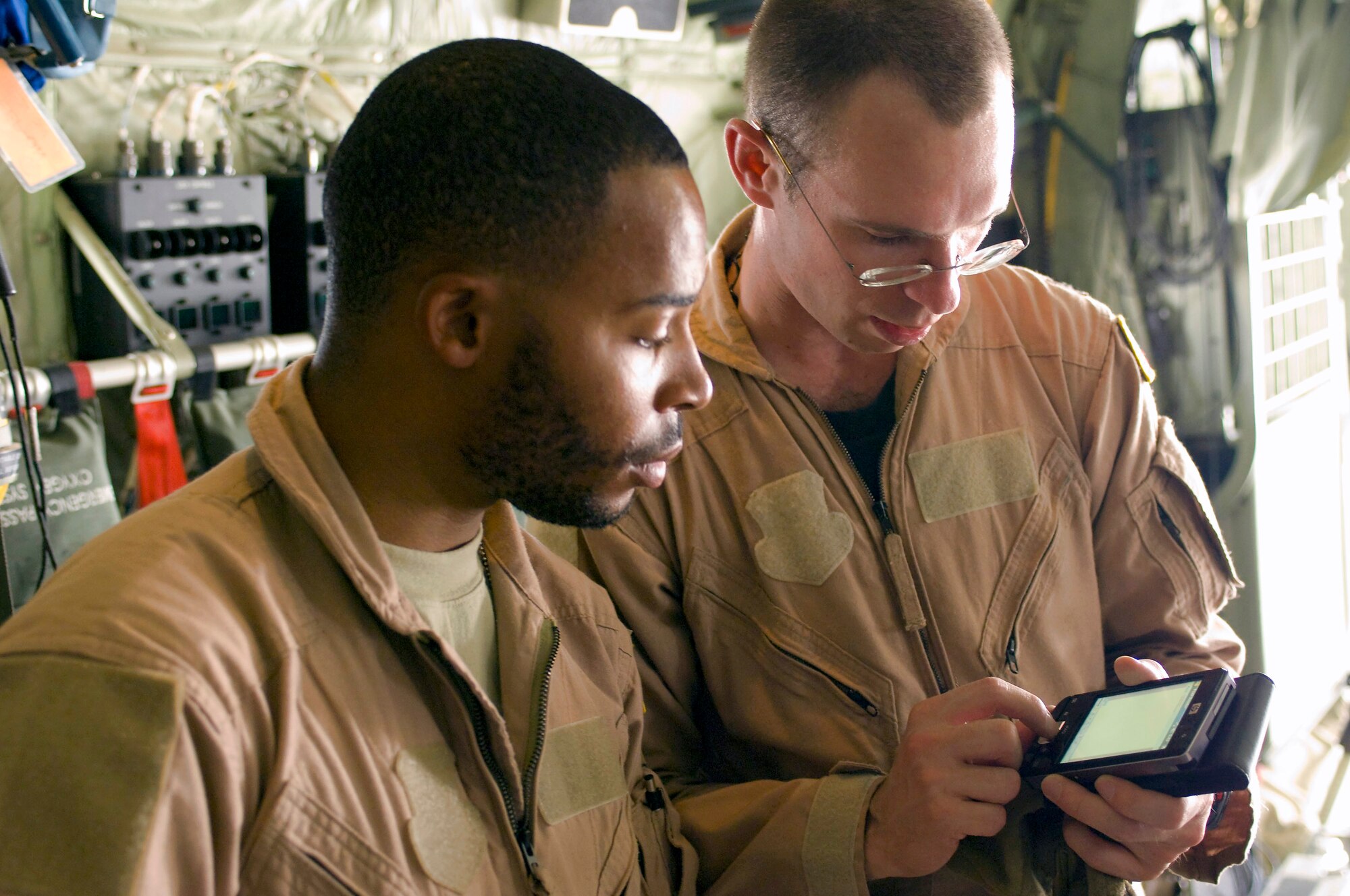 Staff Sgt. Elliot Dozier (left) and Capt. Matthew Rist (right) look up information on a personal digital assistant inside a C-130 Hercules July 8 at Bagram Air Field, Afghanistan. Sergeant Dozier and Captain Rist are deployed to the 455th Expeditionary Aeromedical Evacuation Flight from the 375th Aeromedical Evacuation Squadron at Scott Air Force Base, Ill. (U.S. Air Force photo/Staff Sgt. Samuel Morse) 