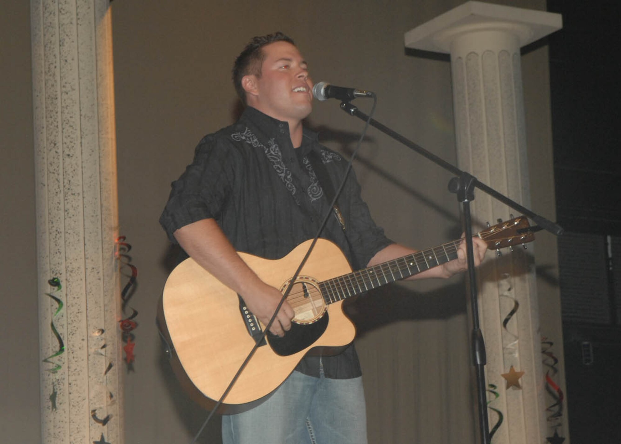 Third place winner, Tech. Sgt. Gary Bonnet, 214th Reconnaissance Squadron intelligence analyst, performs his first song of the evening at the first annual D-M Idol competition held July 11 at the Tucson Magnet High School Auditorium. Sergeant Bonnet, a native of West Virginia, credits his musical success to Texas music superstar, Randy Rogers, and Cody Canada, from Cross Canadian Ragweed. (U.S. Air Force Photo By Senior Airman Melissa Copeland)