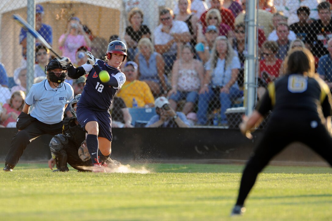 Kelly Kretschman (center), U.S.A. Olympic Softball Team outfielder, hits the ball toward Sarah Seamands (right), Black Hills Gold Softball Team second baseman, at the Pete Lien Memorial Field, Rapid City, S.D., July 15. Kretschman was out at first but that didn't stop the Olympic team from shutting out Black Hills Gold 7-0. (U.S. Air Force photo/Senior Airman Kasey Zickmund)