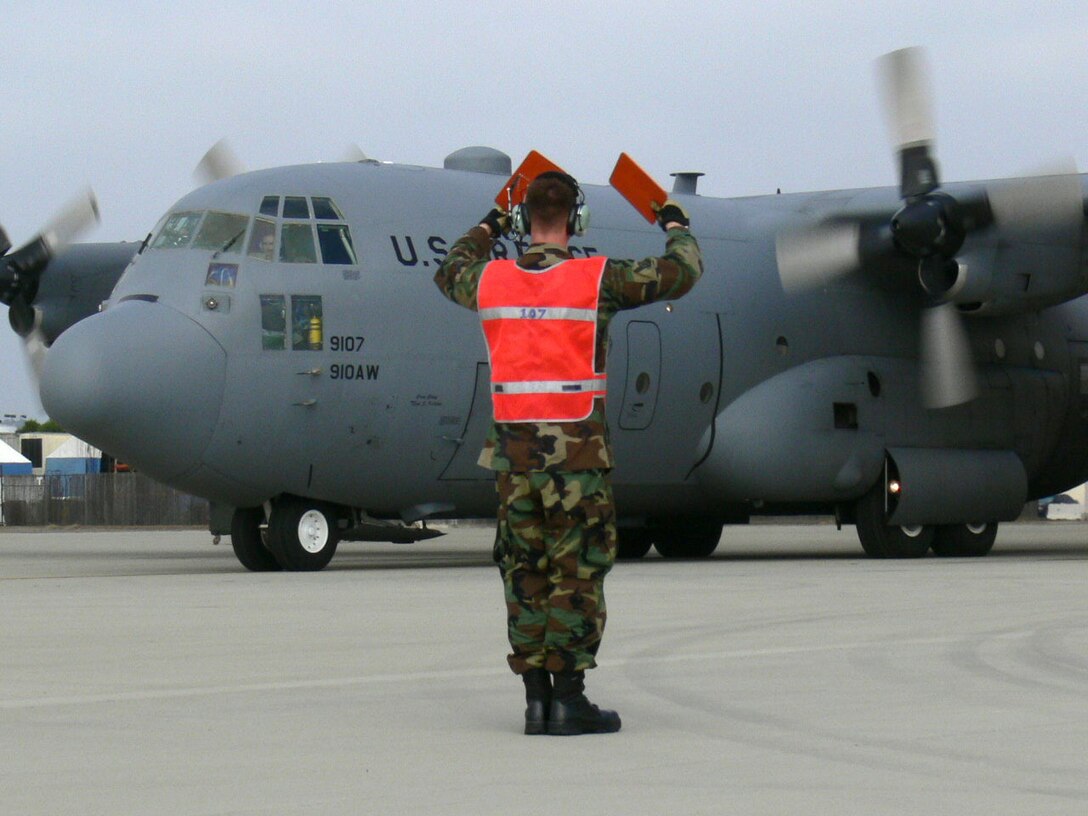 Airman 1st Class Aaron Walghren, 910th Aircraft Maintenance Squadron crew chief, uses orange paddles to marshal an Air Force Reserve C-130H on an aerial spray training mission June 12, 2008 at Naval Air Station North Island, Calif. 
