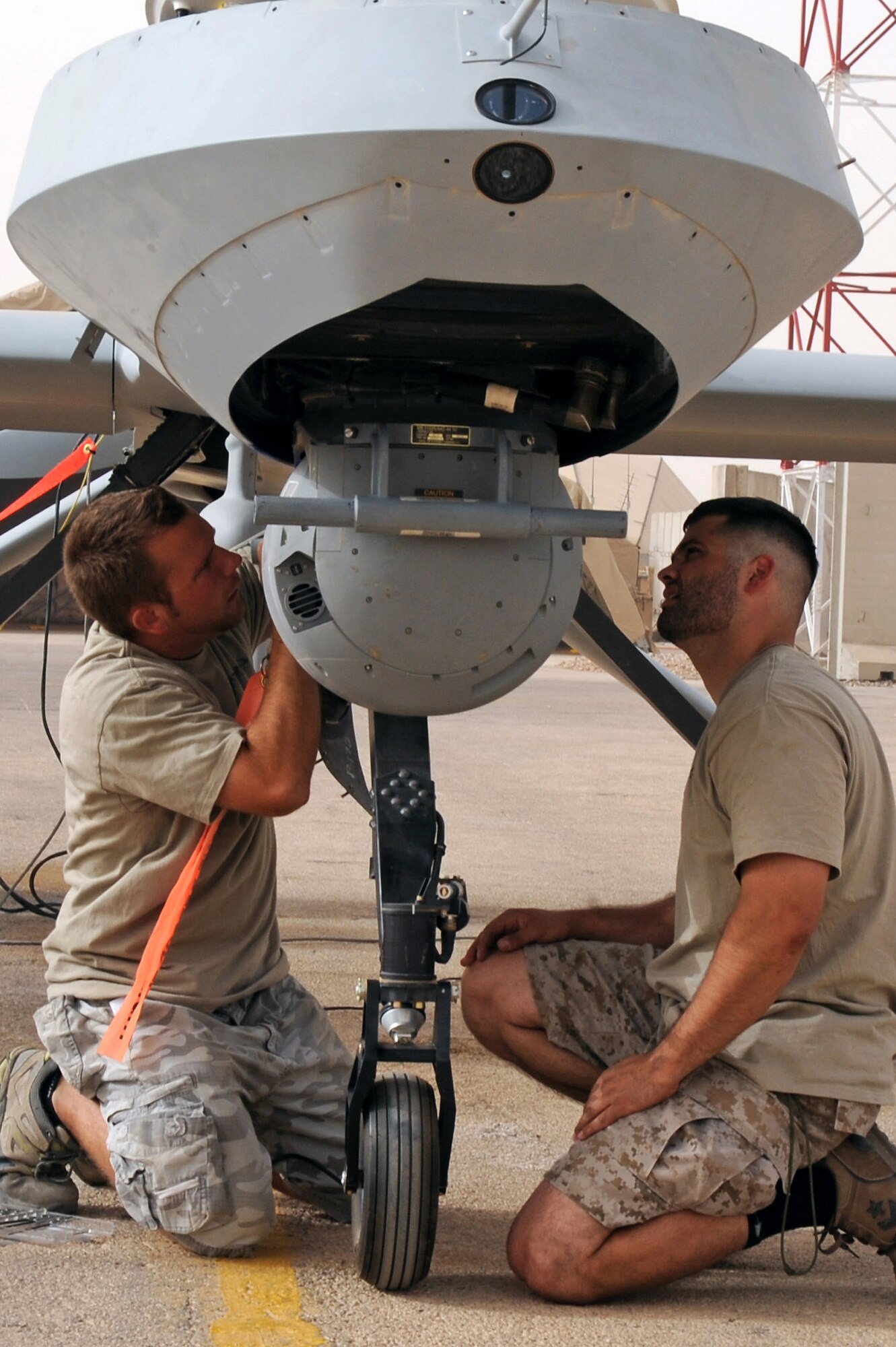 Paul Rudolph and Schuyler Dunn replace a Multispectural Targeting System Ball on an MQ-1B Predator unmanned aircraft July 9 at Ali Base, Iraq. The Predator provides integrated and synchronized close air combat operations, to include intelligence, surveillance and reconnaissance, through the use of advanced capabilities, focused doctrine and detailed training. The two aircraft technicians are assigned to the 361st Expeditionary Reconnaissance Squadron. (U.S. Air Force photo/Tech. Sgt. Sabrina Johnson) 